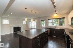 Open-concept living area featuring dark wood-finish flooring, a built-in fireplace with a white mantel, and recessed lighting - 