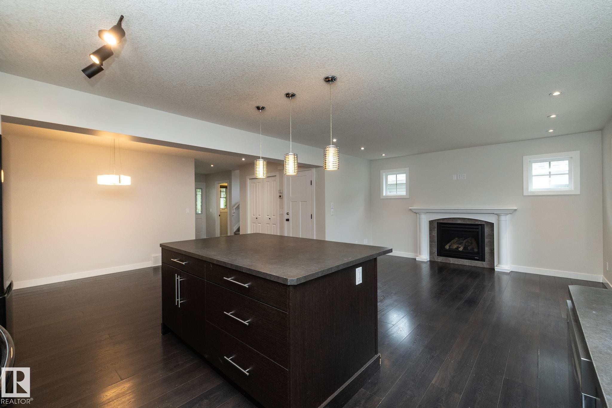 Kitchen island with dark cabinetry and a stone-finish countertop - 53/55 Michigan Street, Devon, AB