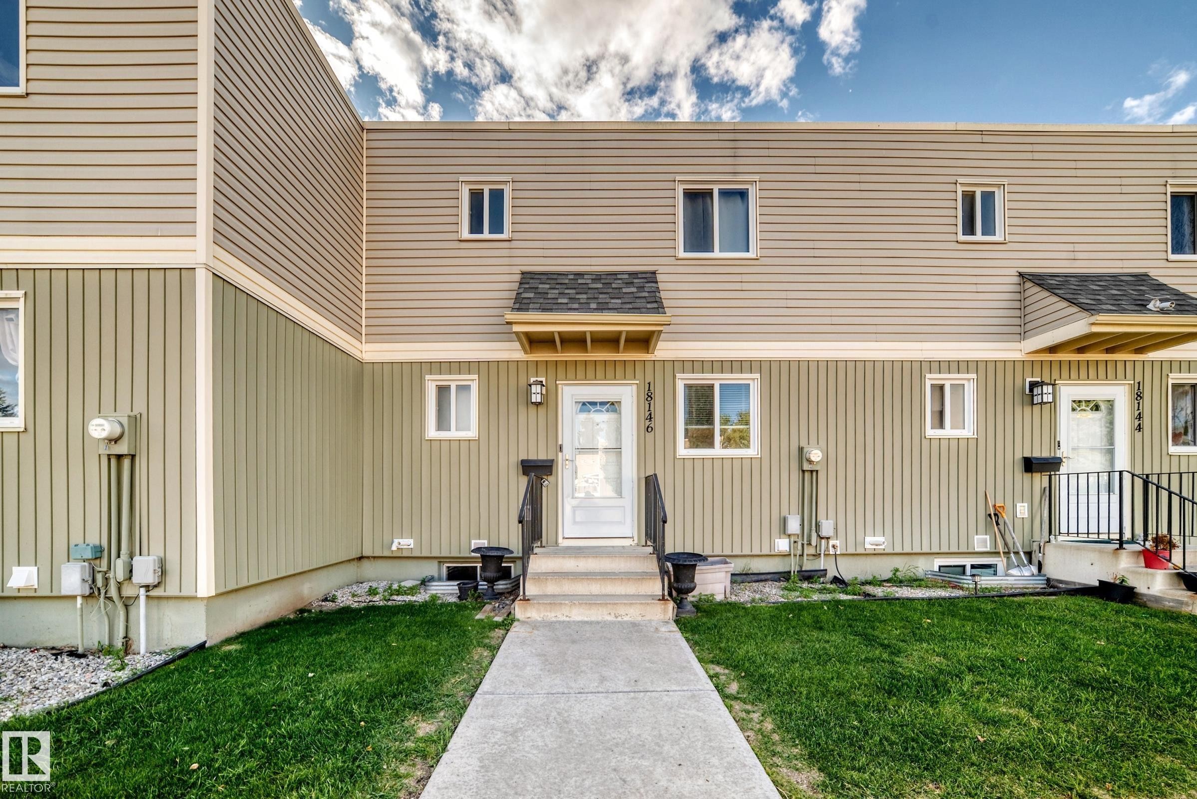Two-story townhome with tan horizontal siding and vertical paneling - 18146 81 Avenue Nw, Edmonton, AB