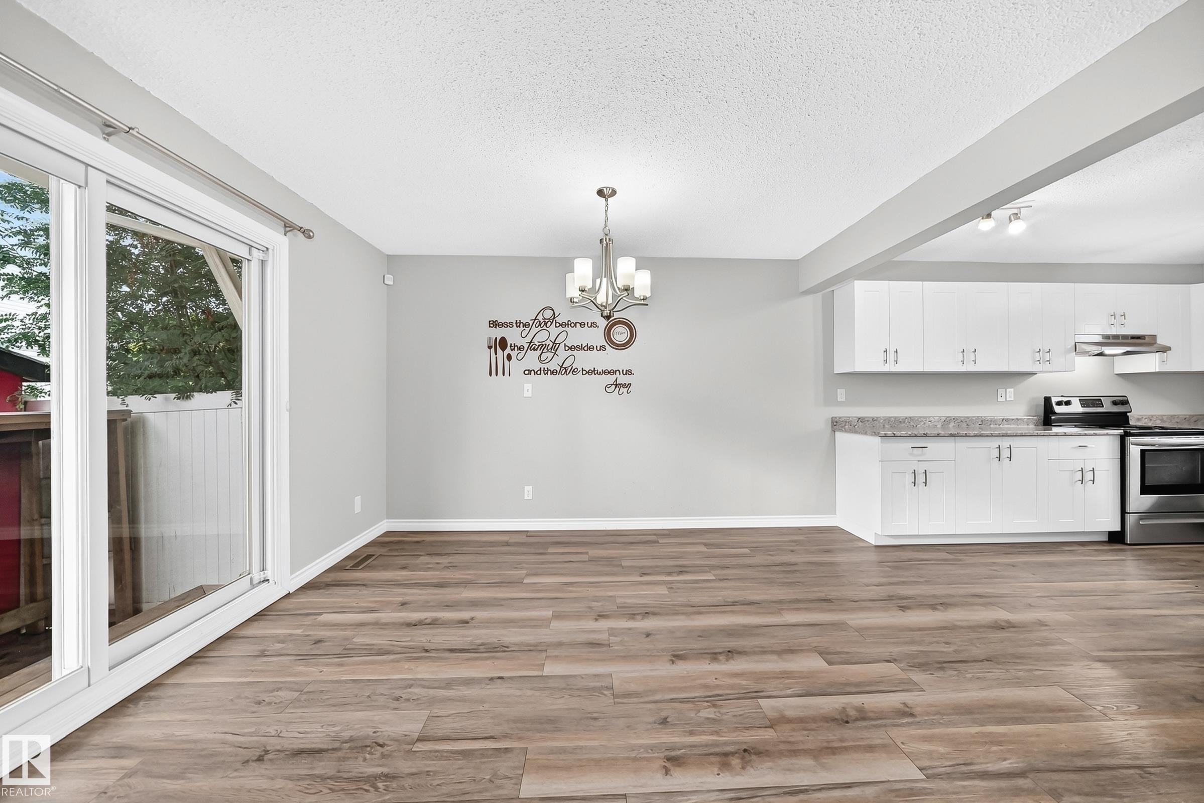 Wood-finish flooring, white cabinetry, integrated stainless steel appliances, granite-look countertops, and a sliding glass door - 18146 81 Avenue Nw, Edmonton, AB