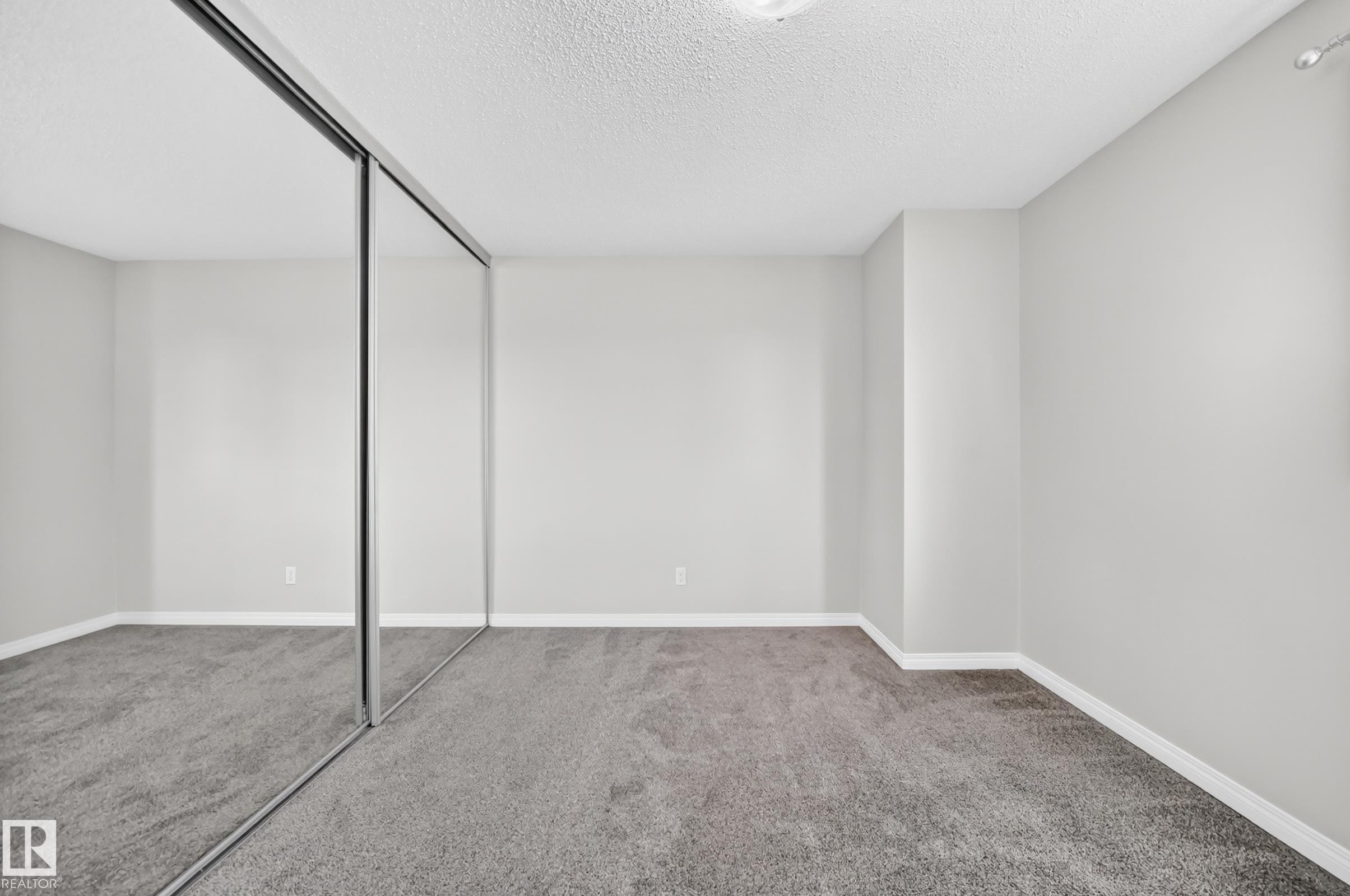 Wall-to-wall mirrored closet doors, neutral wall paint, and gray textured carpeting - 18146 81 Avenue Nw, Edmonton, AB