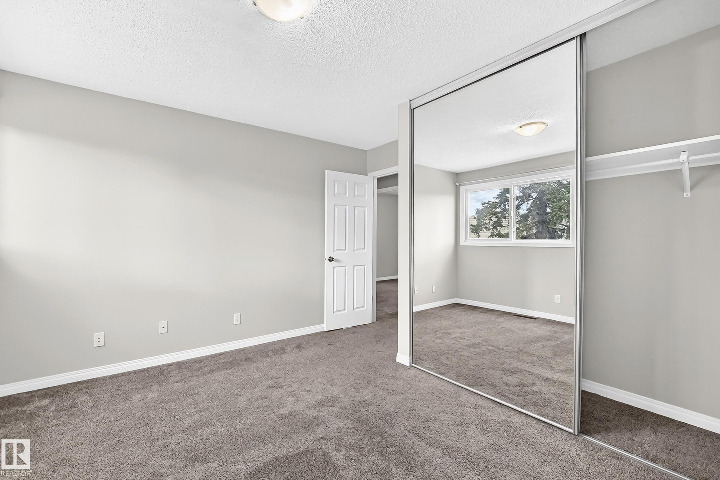 Wall-to-wall carpeting with light gray walls, mirrored closet doors, and built-in closet shelving - 18146 81 Avenue Nw, Edmonton, AB