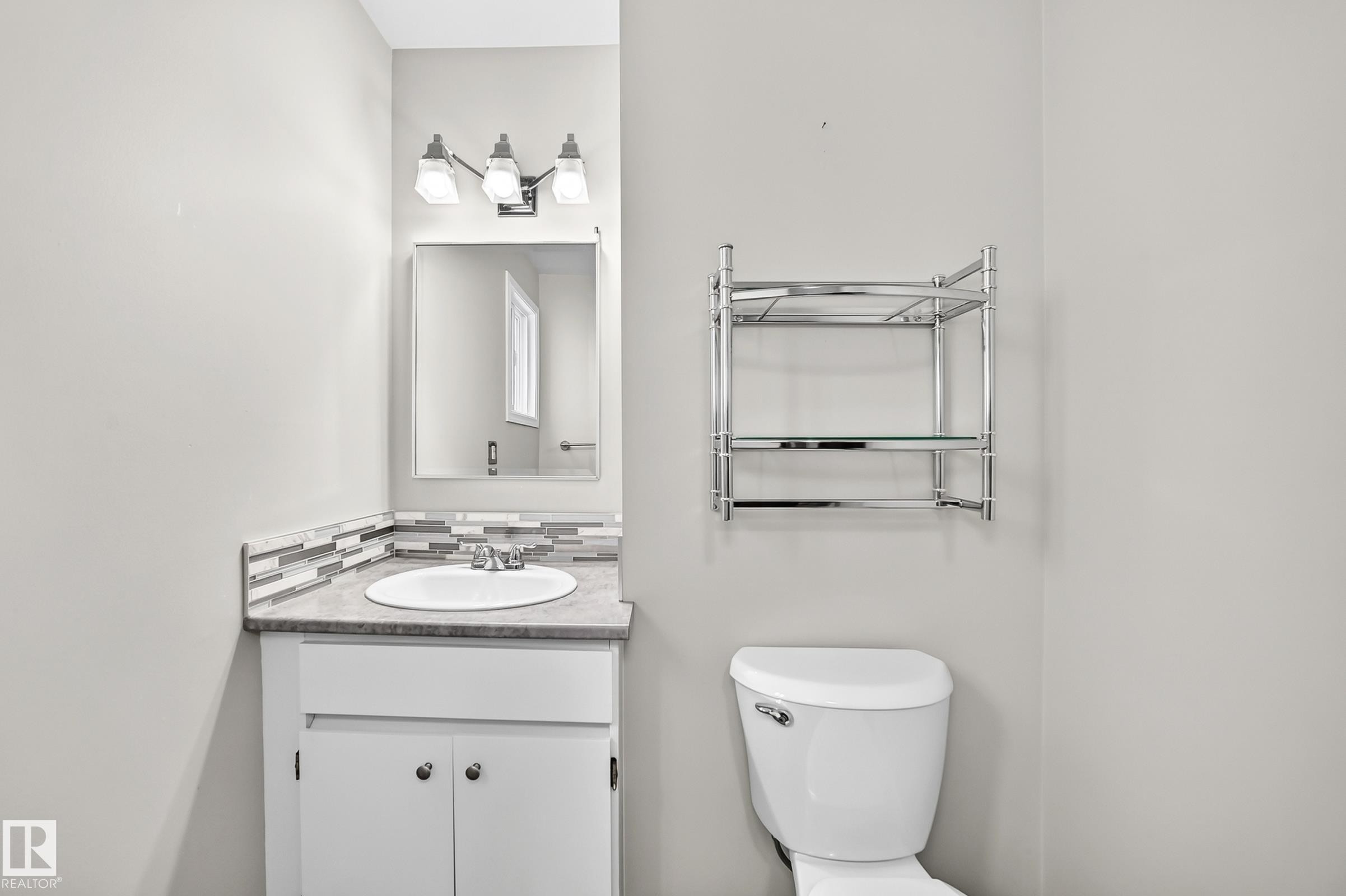 Vanity with an integrated sink, mosaic tile backsplash, and overhead light fixture - 18146 81 Avenue Nw, Edmonton, AB