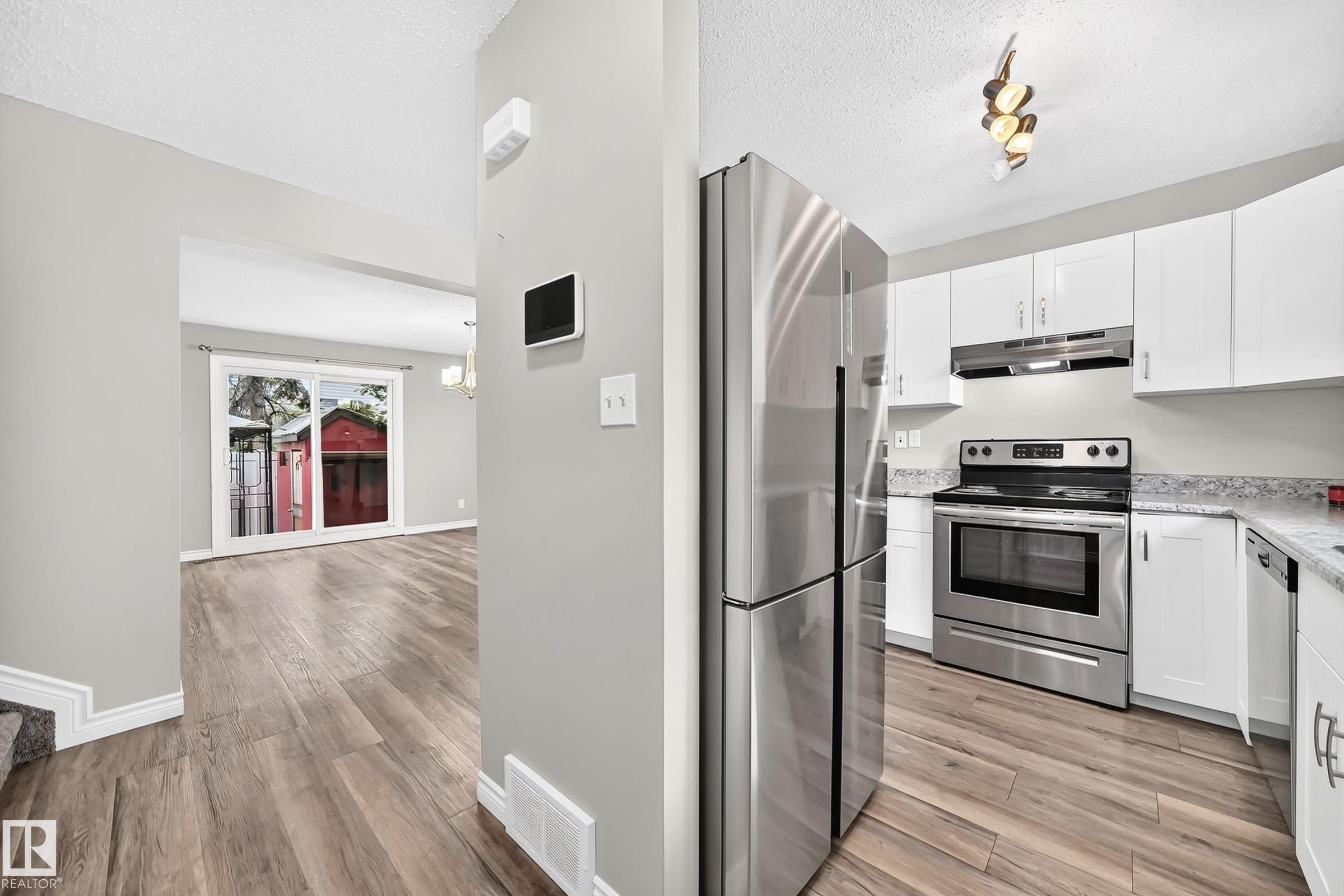 Modern kitchen with stainless steel appliances, white cabinetry, and light-toned countertops - 18146 81 Avenue Nw, Edmonton, AB
