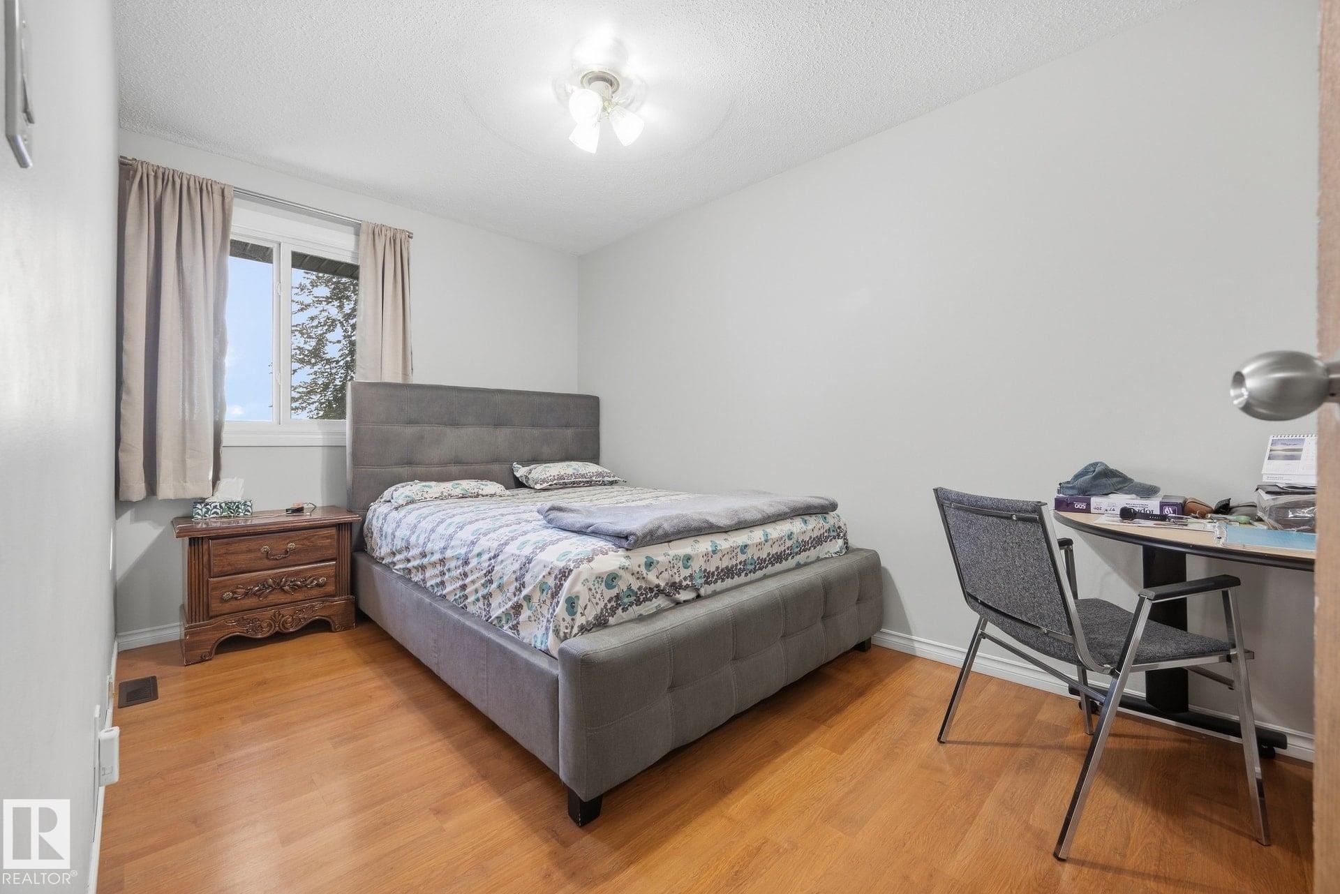 Wood-finish flooring with white baseboards, a window with white trim, and a ceiling-mounted light fixture - #2 14120 80 St Nw, Edmonton, AB