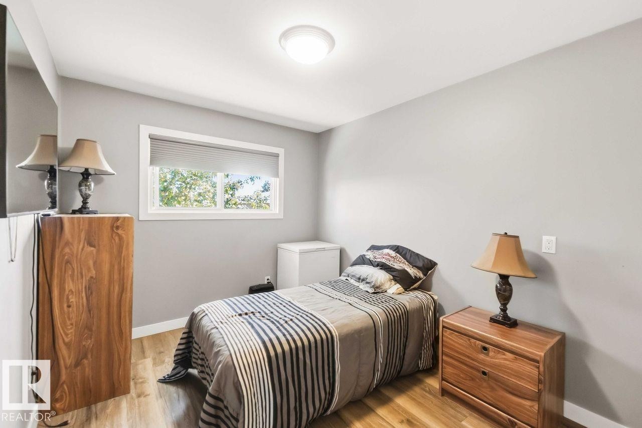 Light wood-finish flooring, white trim, window with blinds, and flush mount lighting - 13427 83 Street Nw, Edmonton, AB