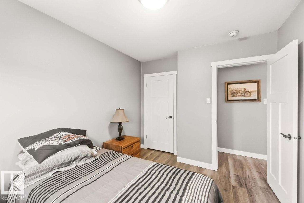 Wood-finish flooring, white trim throughout, and white interior doors with black hardware - 13427 83 Street Nw, Edmonton, AB