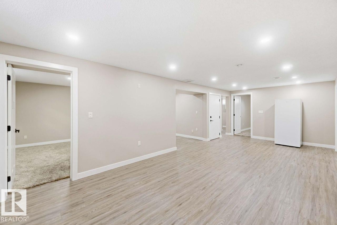 Spacious room featuring light wood-finish flooring, recessed lighting, and multiple doorways - 13427 83 Street Nw, Edmonton, AB