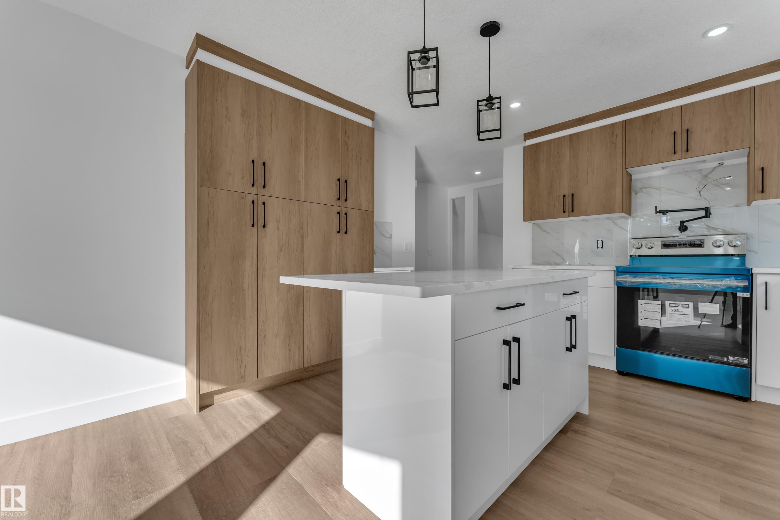 White kitchen island with a solid surface countertop, wood-finish flooring, full-height wood-finish cabinetry, white upper and lower cabinetry, and recessed lighting - 3320 43 Street Nw, Edmonton, AB