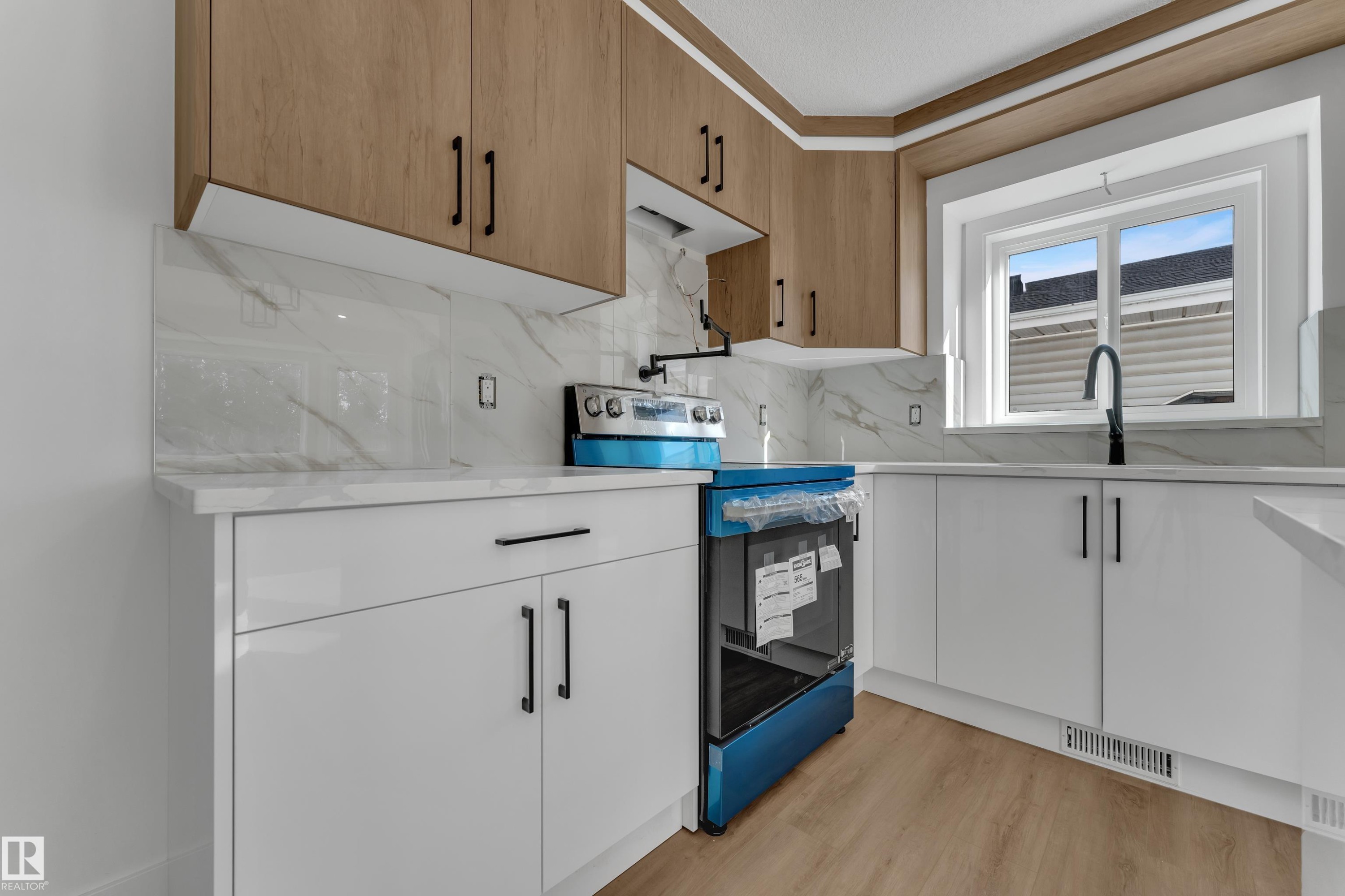 Two-tone cabinetry with wood-finish upper cabinets and white lower cabinets, solid-surface countertops, and a full tile backsplash - 3320 43 Street Nw, Edmonton, AB