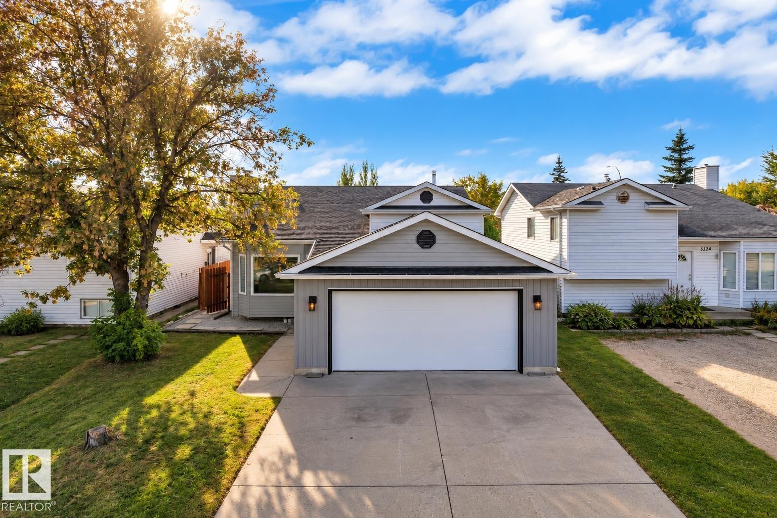 Contemporary exterior with gray siding, attached garage, and a concrete driveway - 3320 43 Street Nw, Edmonton, AB