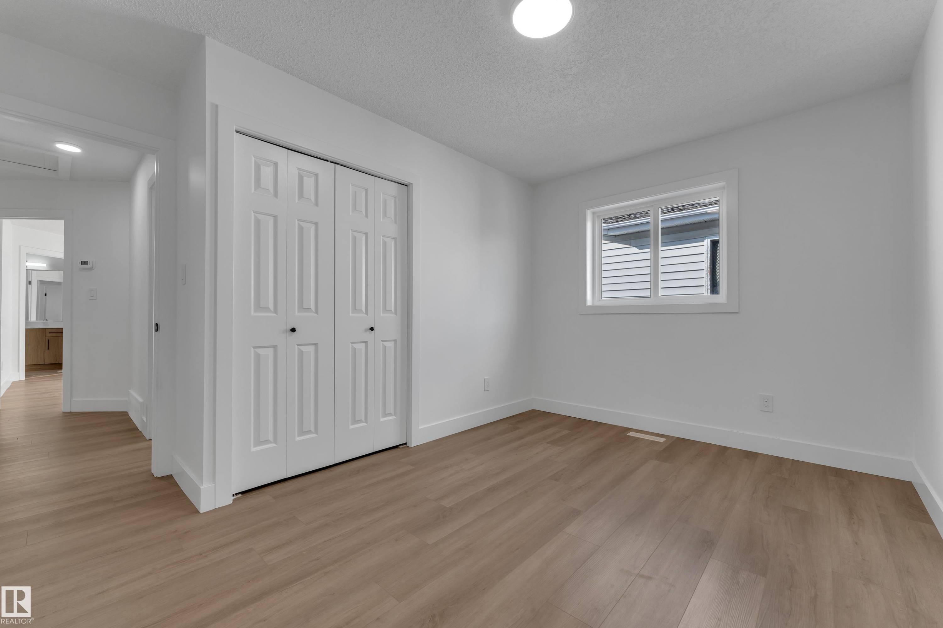 Wood-finish flooring, white walls, white trim, white bi-fold closet doors, and an overhead light fixture - 3320 43 Street Nw, Edmonton, AB