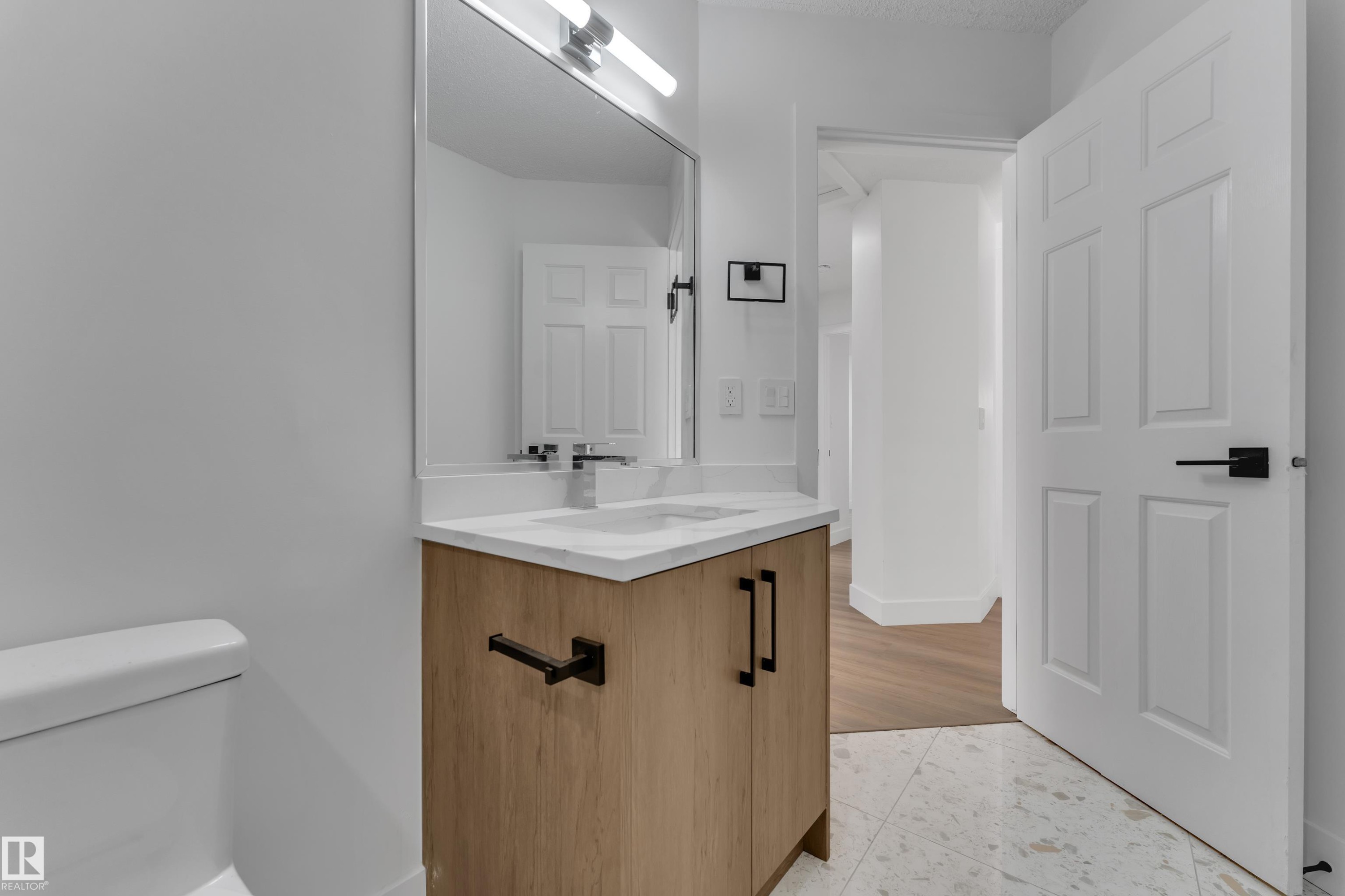 Bathroom featuring a light-toned wood-finish vanity with a white countertop and rectangular undermount sink - 3320 43 Street Nw, Edmonton, AB