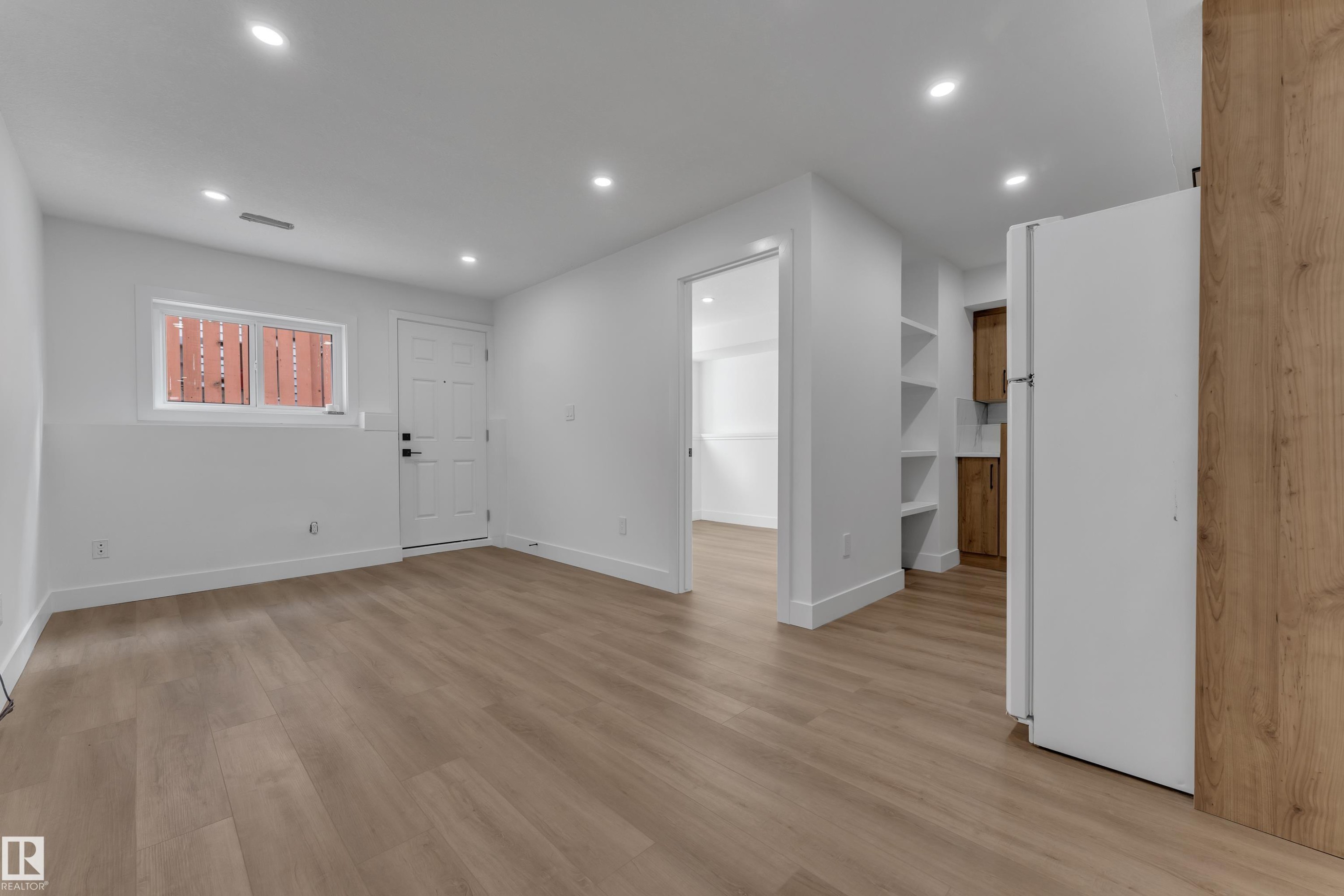 Light wood-finish flooring, recessed ceiling lights, built-in shelving, white walls, and a contemporary white door - 3320 43 Street Nw, Edmonton, AB