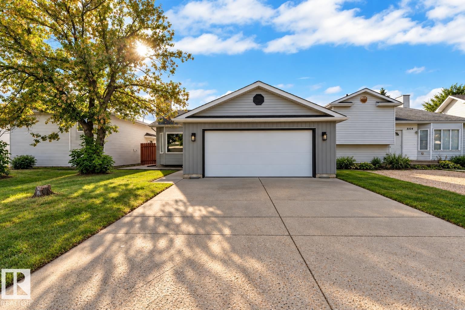 Gray horizontal siding exterior with a white garage door, concrete driveway, and front lawn - 3320 43 Street Nw, Edmonton, AB