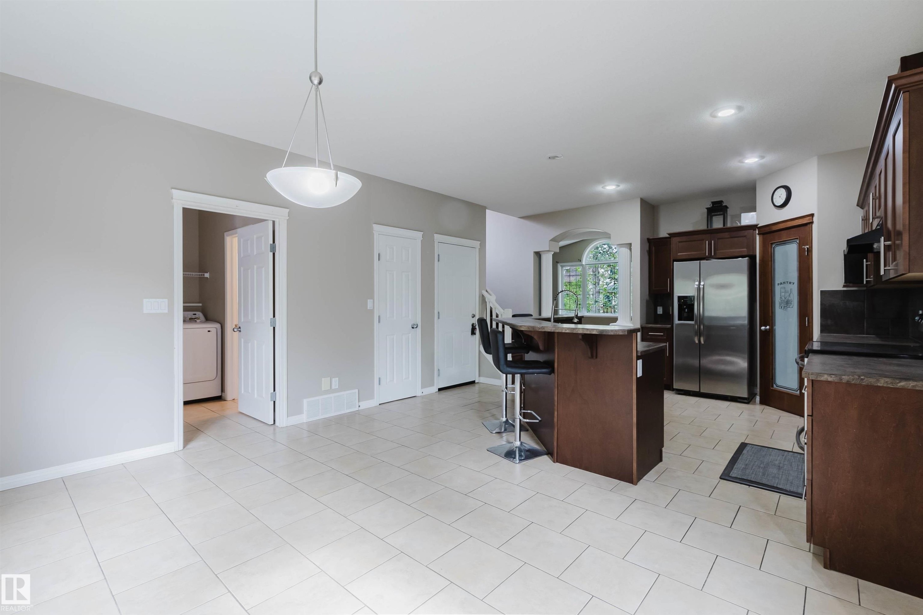 Tile flooring, kitchen island with breakfast bar, wood cabinetry, stainless steel refrigerator, and recessed lighting - 11608 96 Street Nw, Edmonton, AB