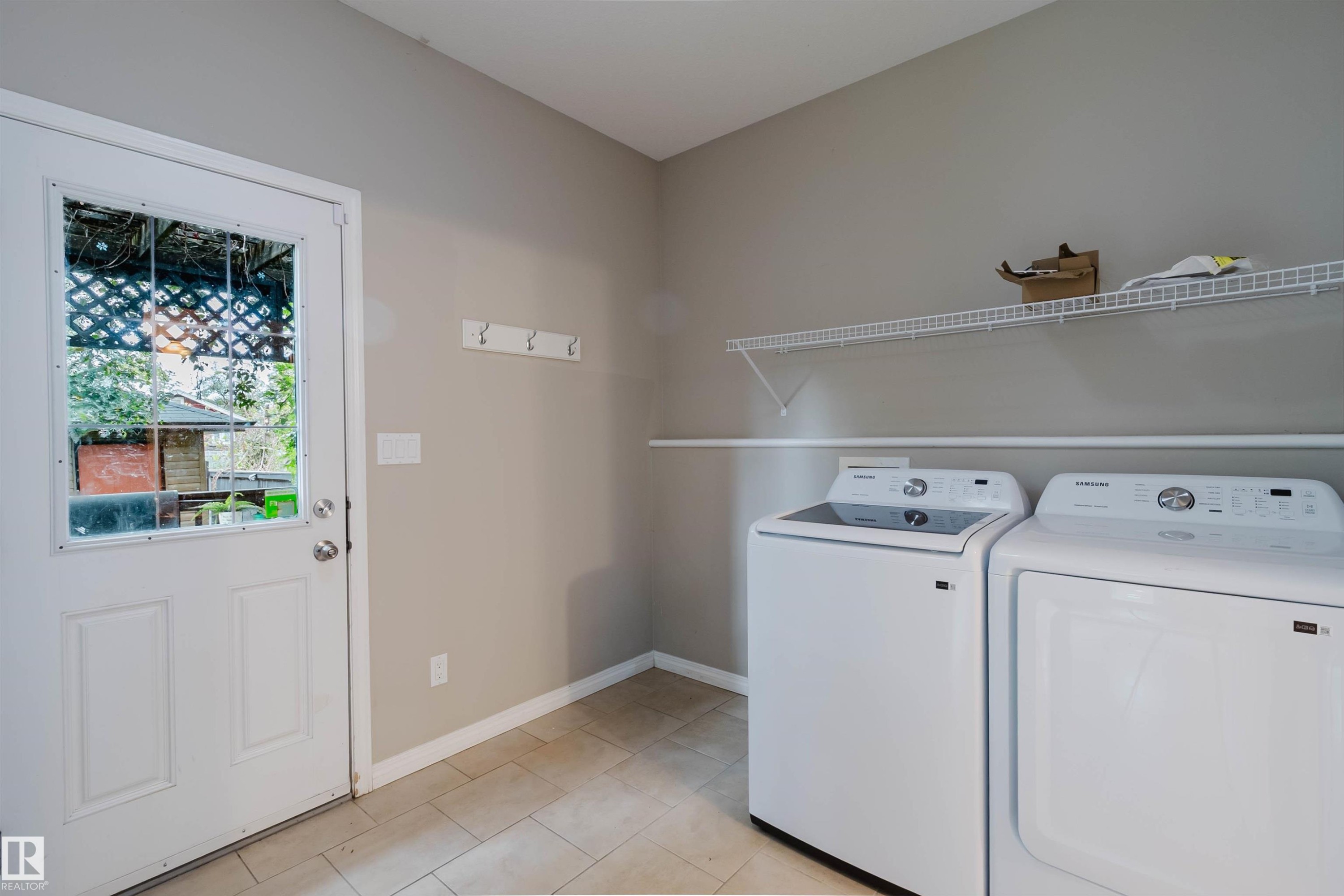 Neutral wall paint, tiled flooring, white wire shelving, wall-mounted coat rack, and a glass-paneled door - 11608 96 Street Nw, Edmonton, AB