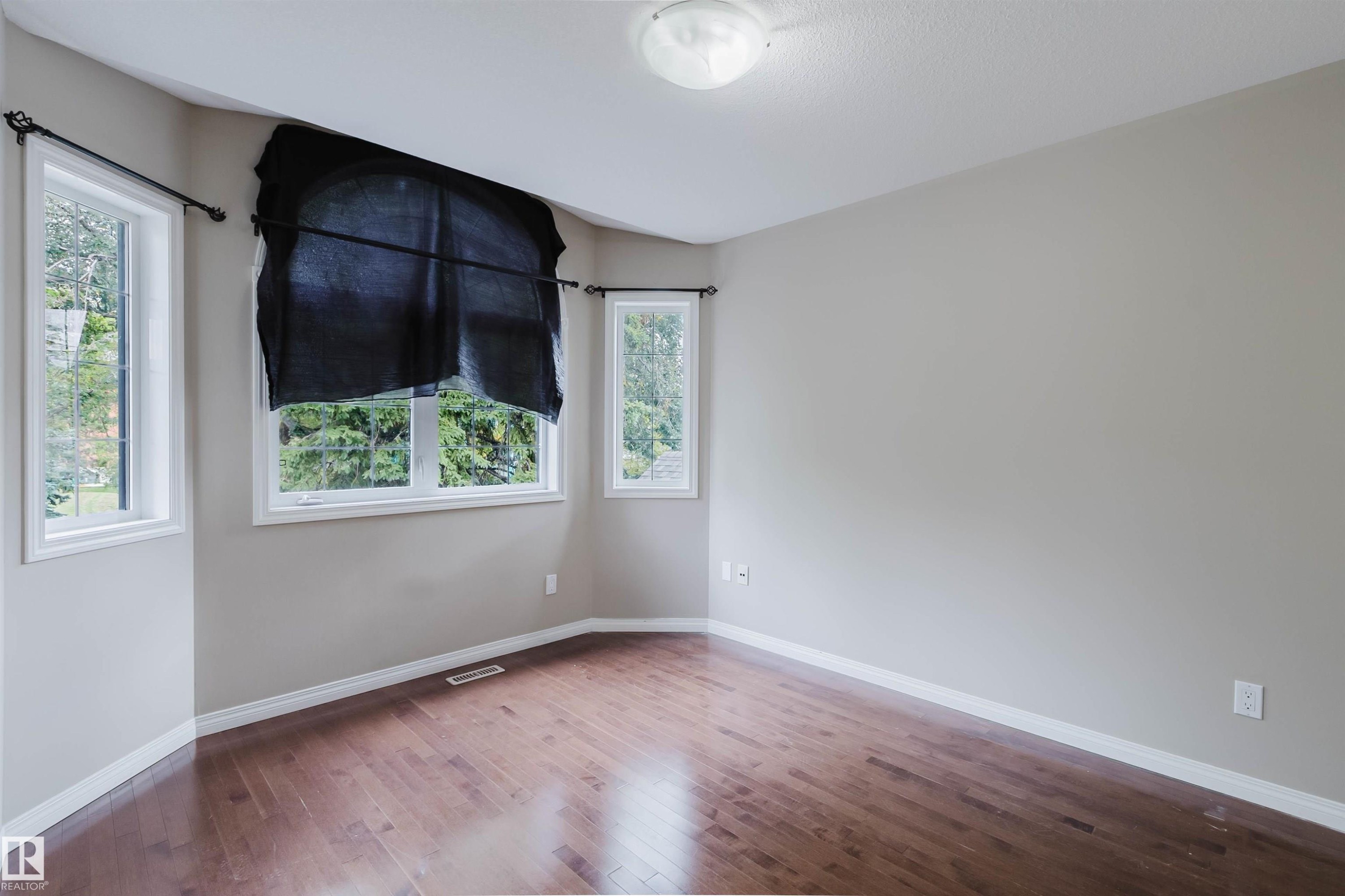 Hardwood-finish flooring, light-toned wall paint, multiple windows, white trim, and a ceiling-mounted light fixture - 11608 96 Street Nw, Edmonton, AB