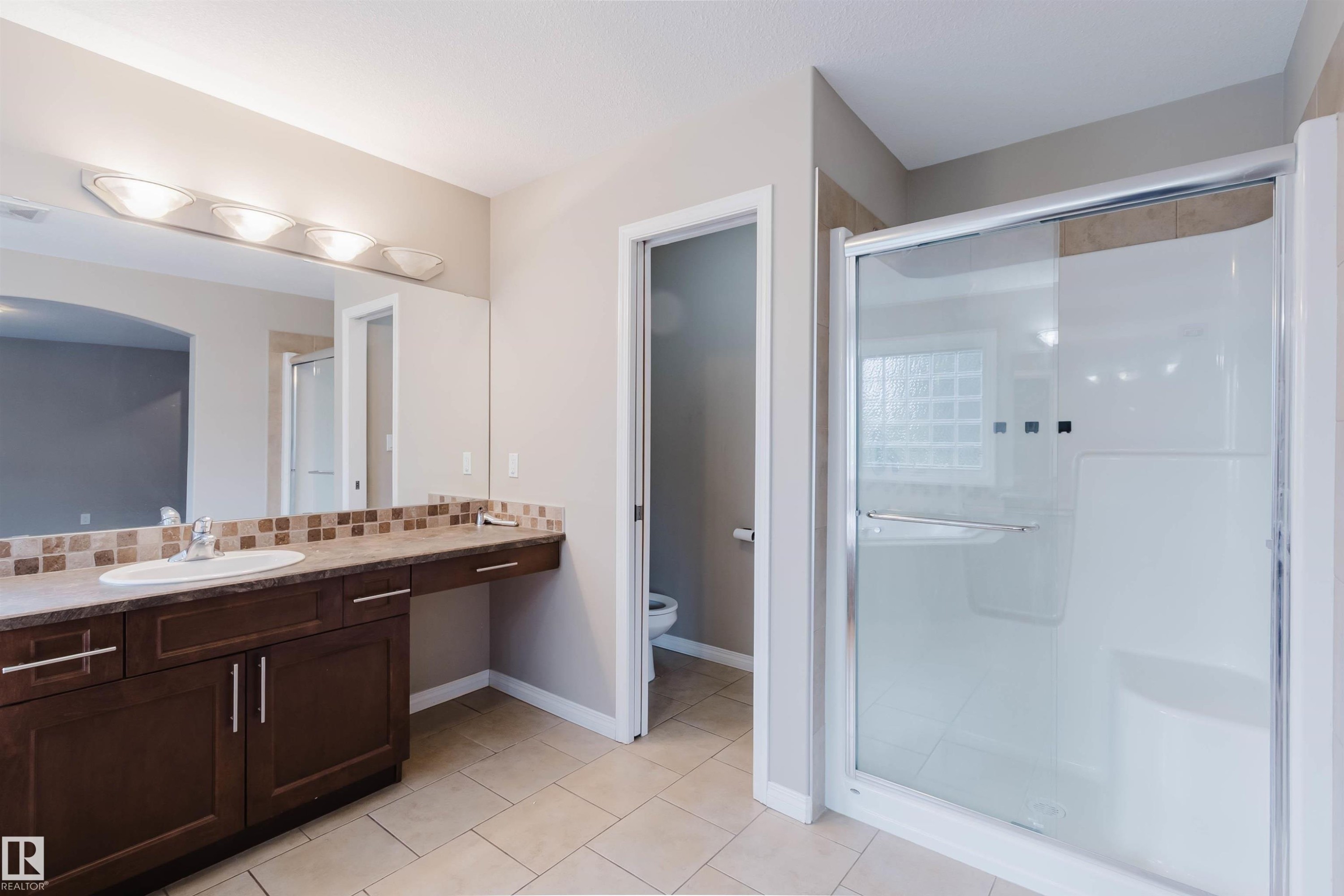 Bathroom featuring a single vanity, a tiled backsplash, and a glass-enclosed shower with tiled walls - 11608 96 Street Nw, Edmonton, AB