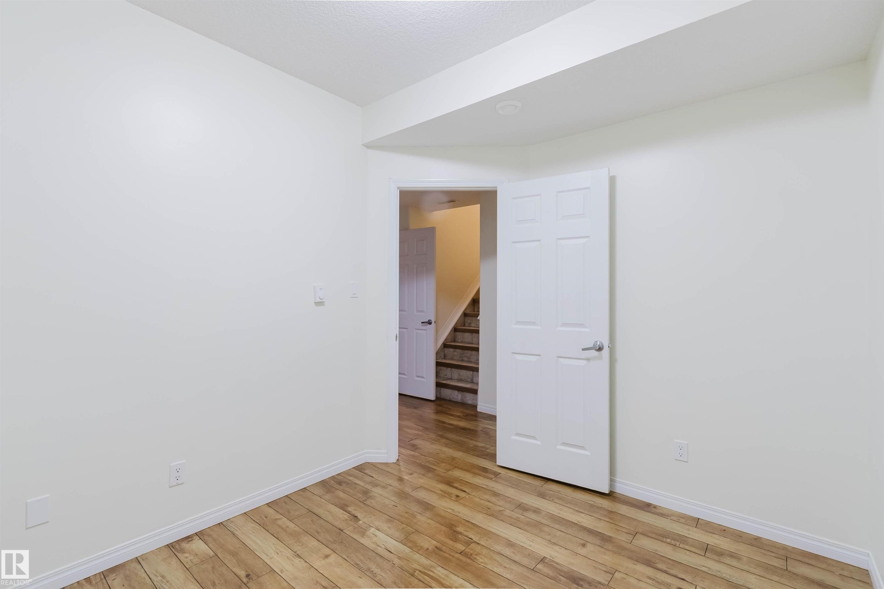 Wood-finish flooring with white trim and neutral wall finishes - 11608 96 Street Nw, Edmonton, AB