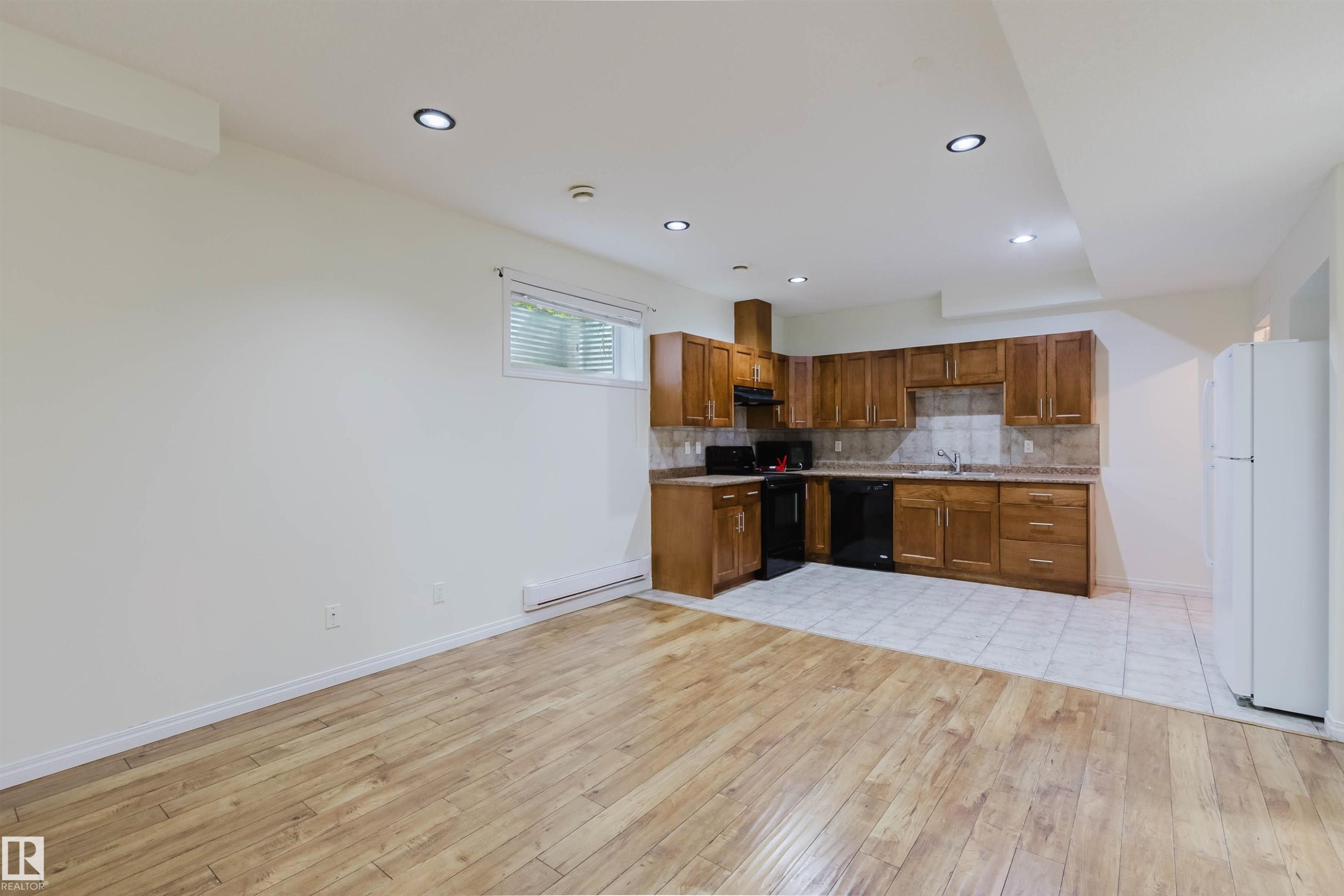 Open-concept living space with wood-finish flooring, recessed lighting, and a window for natural illumination - 11608 96 Street Nw, Edmonton, AB