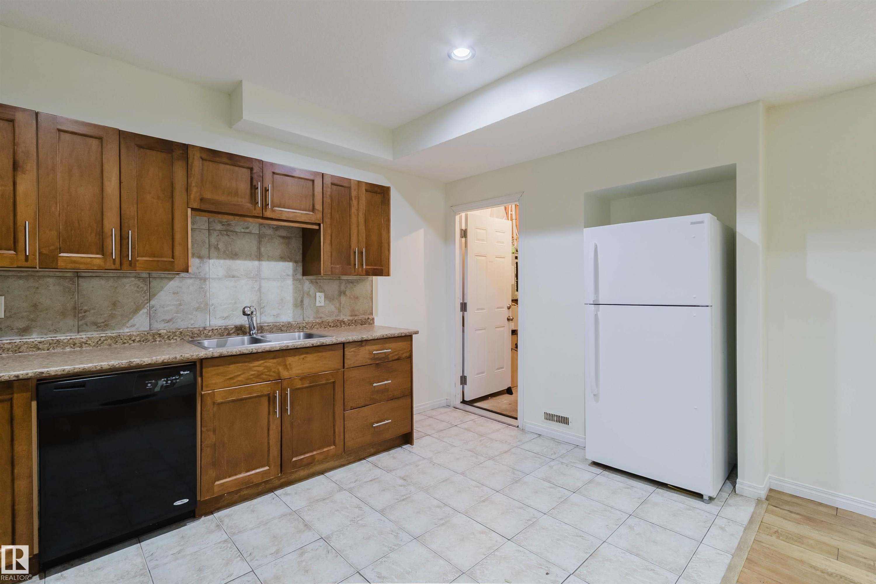 Kitchen featuring wood-finish cabinetry, tile backsplash, built-in dishwasher, and recessed ceiling lighting - 11608 96 Street Nw, Edmonton, AB