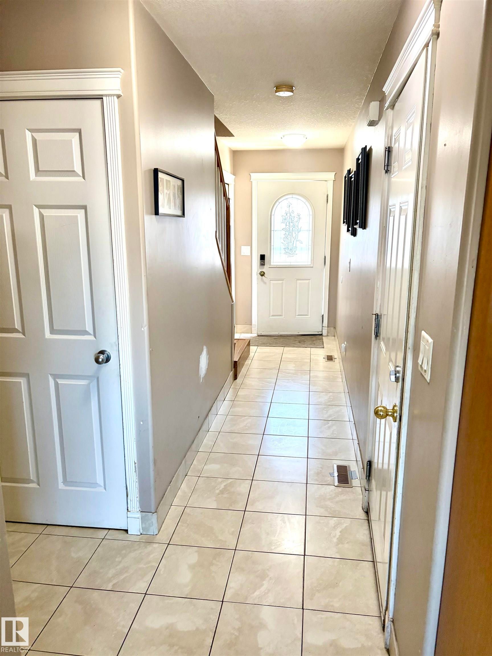 Tiled flooring with neutral tones throughout this hallway - #17 16317 64 St Nw, Edmonton, AB