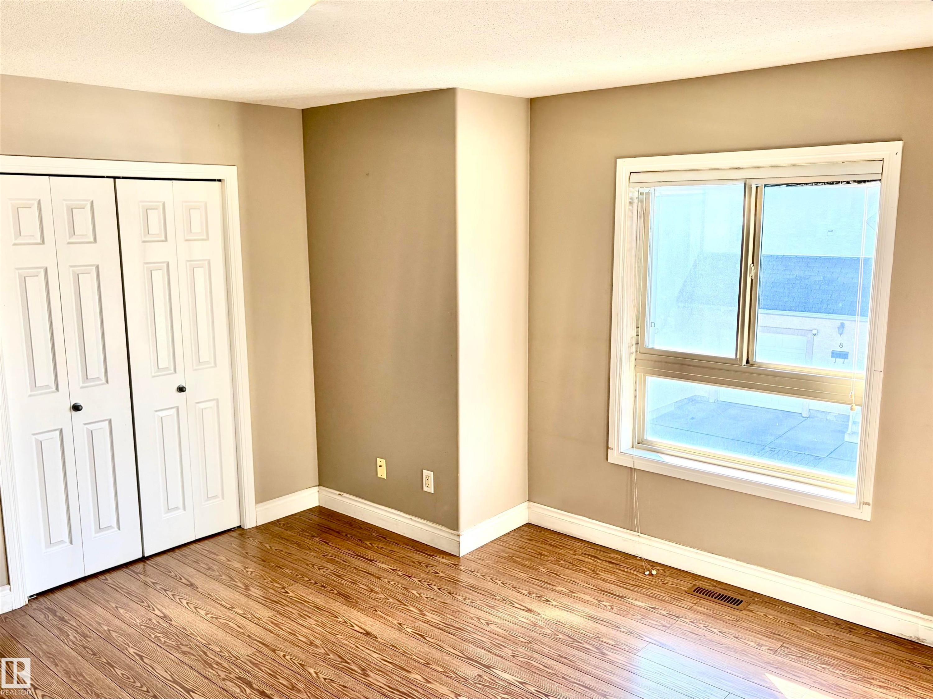 Wood-finish flooring, neutral wall tones, white trim, and a window for natural illumination - #17 16317 64 St Nw, Edmonton, AB