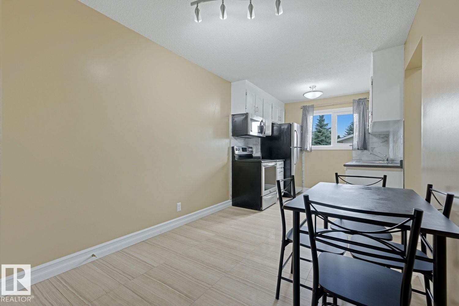 Recessed lighting, wood-finish flooring, white cabinetry, dark appliances, and a window - 11317 22 Avenue Nw, Edmonton, AB