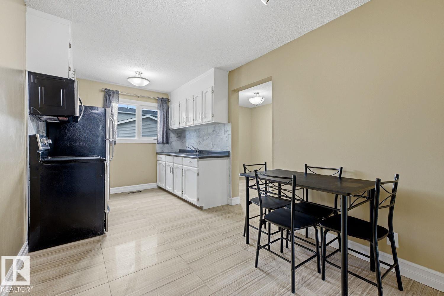 Kitchen featuring white cabinetry, black appliances, a double basin sink, and tile flooring - 11317 22 Avenue Nw, Edmonton, AB