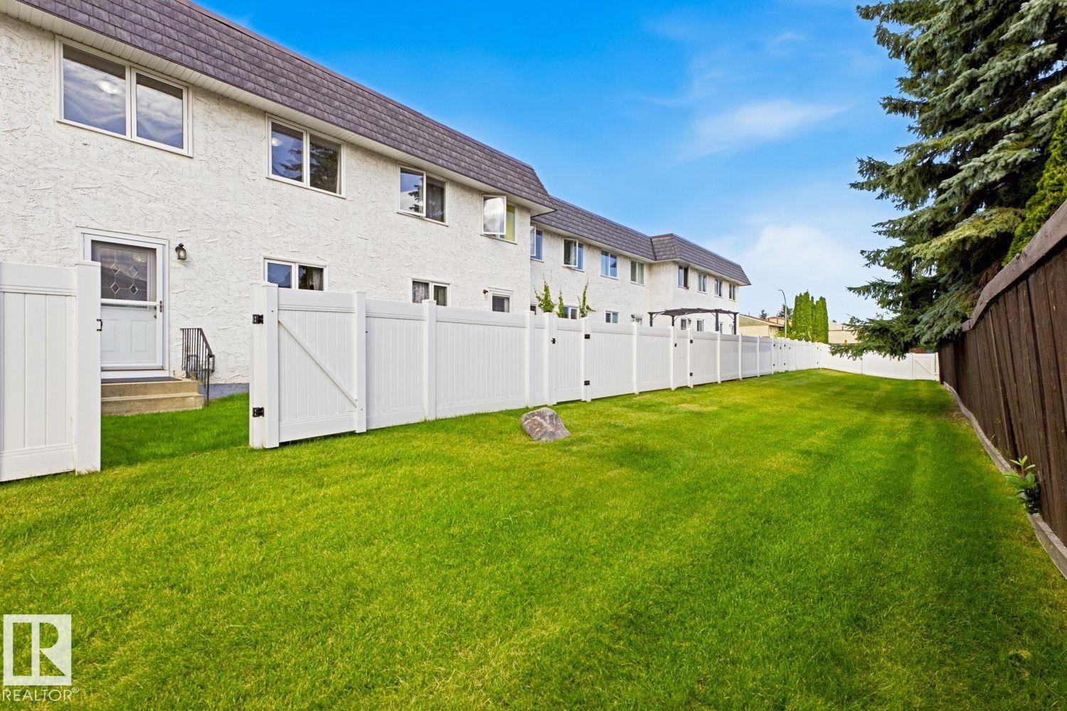 Expansive green lawn enclosed by white panel fencing - 11317 22 Avenue Nw, Edmonton, AB