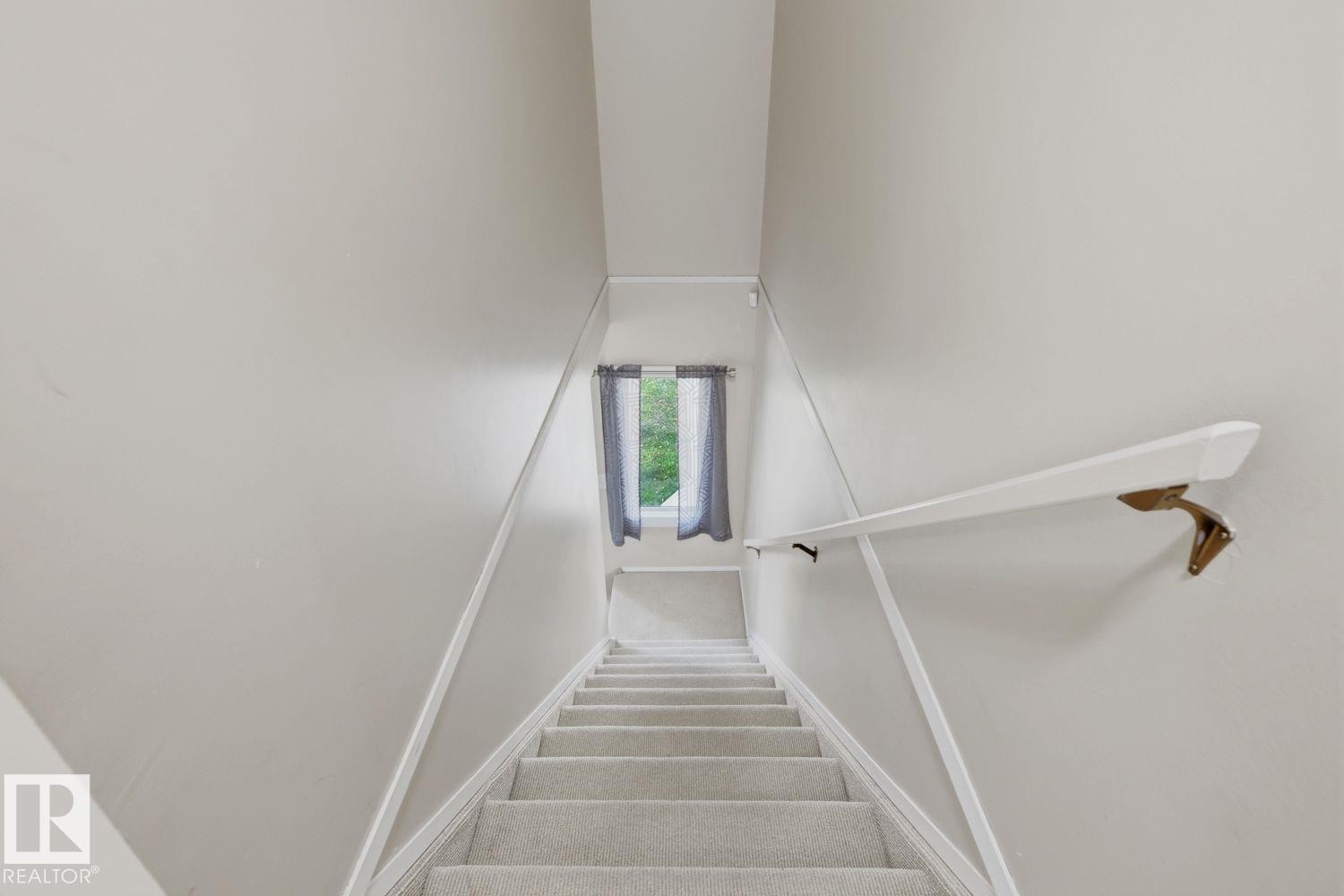 Carpeted staircase with wall-mounted handrail, leading to an upper level with a window - 11317 22 Avenue Nw, Edmonton, AB