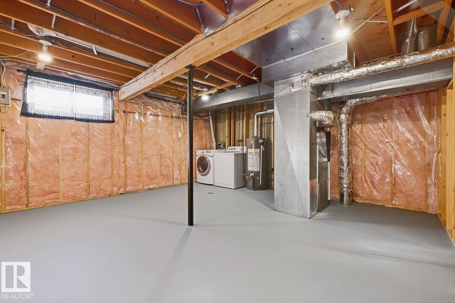 Utility space featuring exposed wood beams, a painted concrete floor, and a window with a security grate - 11317 22 Avenue Nw, Edmonton, AB
