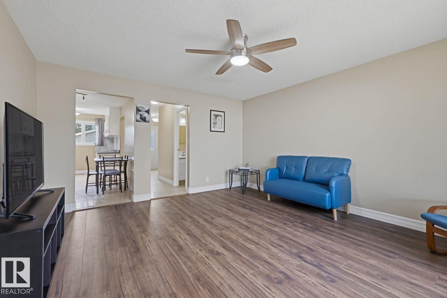 Wood-finish flooring throughout, complemented by a ceiling fan with integrated lighting - 11317 22 Avenue Nw, Edmonton, AB