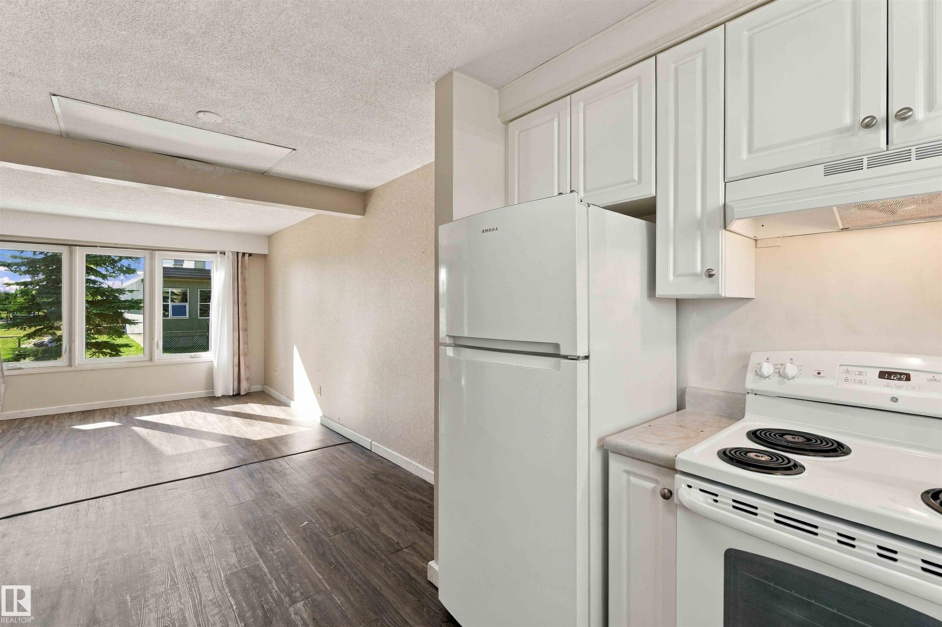 White kitchen cabinetry with a light-toned countertop, accompanied by a white refrigerator and range - 17351 85 Avenue Nw, Edmonton, AB