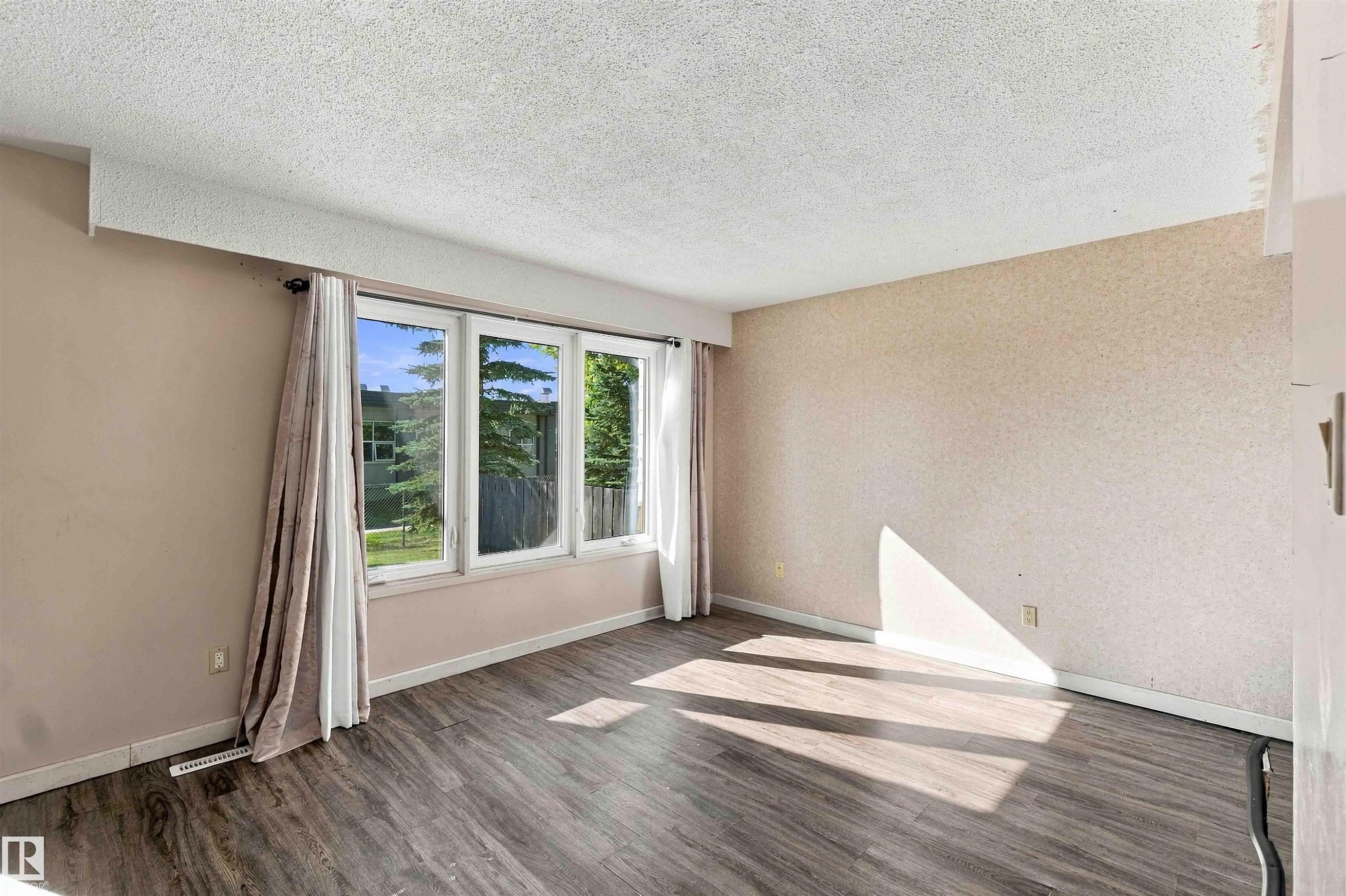 Wood-finish flooring, textured wall finishes, and a multi-pane window with drapery rods - 17351 85 Avenue Nw, Edmonton, AB