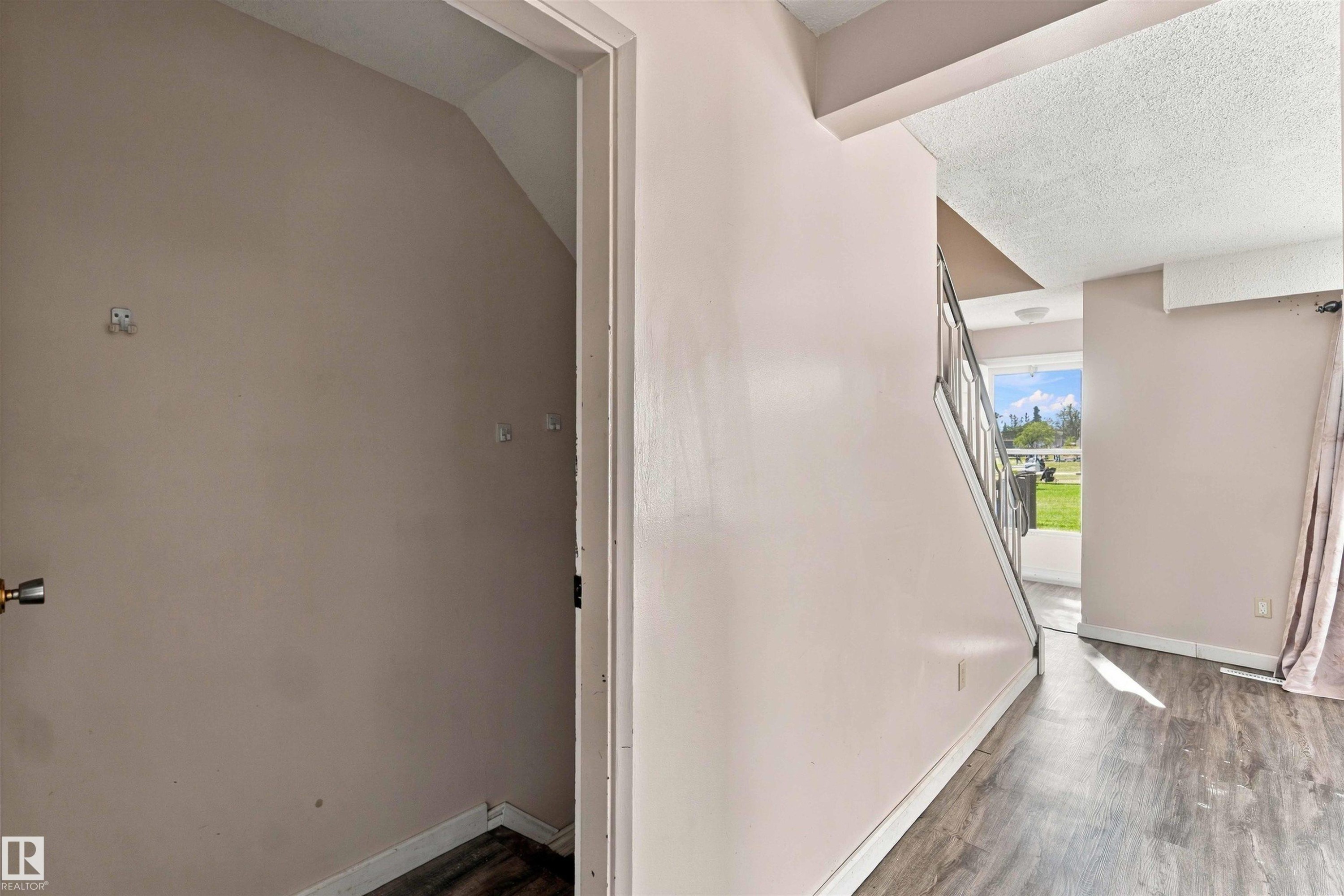 Wood-finish flooring throughout, staircase with metal railings, and natural light from exterior - 17351 85 Avenue Nw, Edmonton, AB