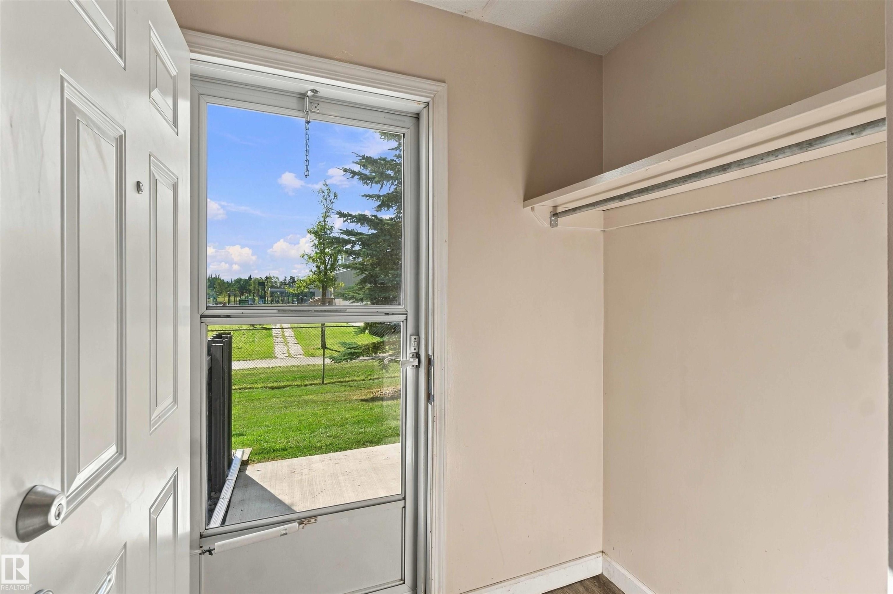 Entryway featuring a panel door, screen door, and built-in closet with hanging rod - 17351 85 Avenue Nw, Edmonton, AB