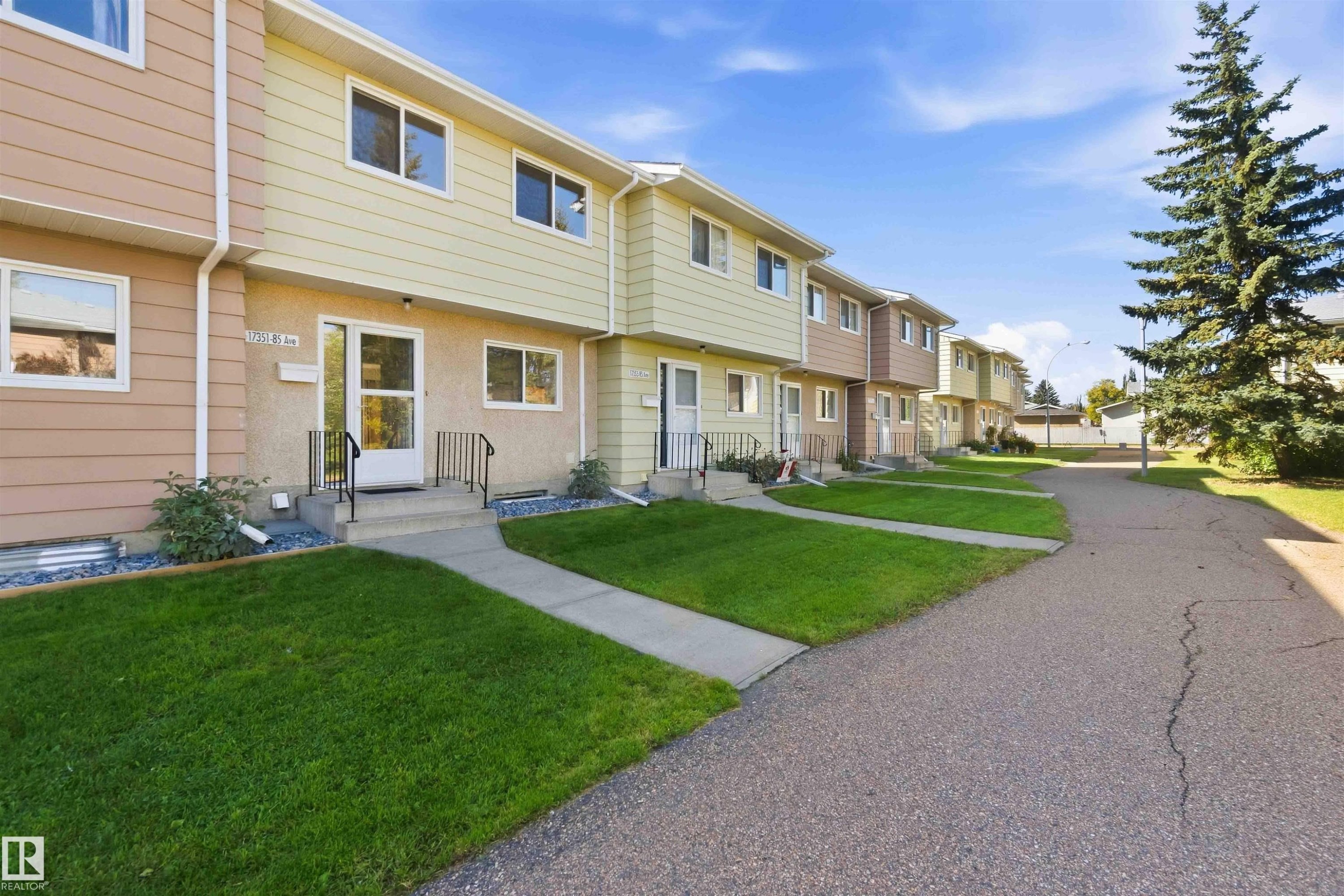 Multi-unit residential structure with individual entrances, front lawns, and paved pathways - 17351 85 Avenue Nw, Edmonton, AB