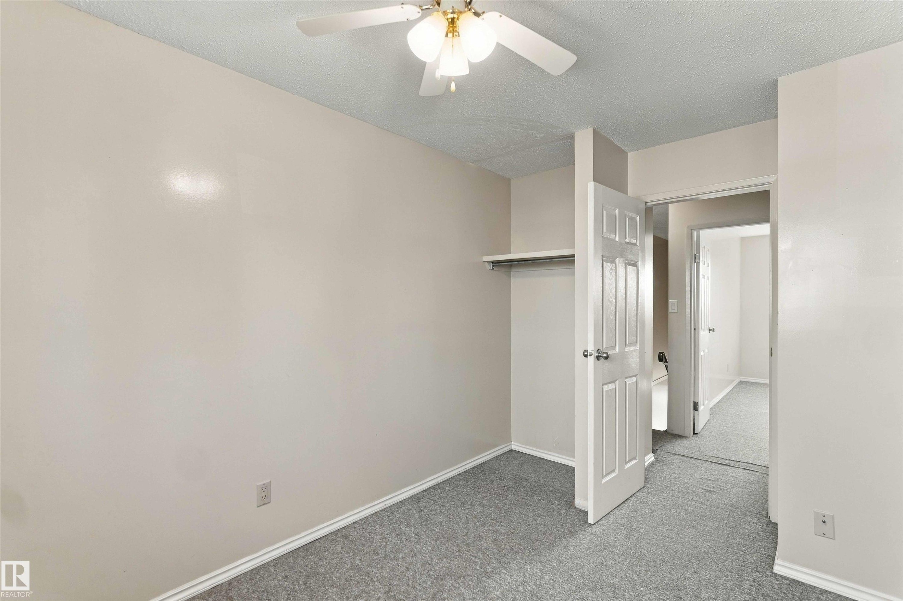 Neutral wall finishes, textured ceiling, ceiling fan, carpet flooring, and a built-in closet shelf with hanging rod - 17351 85 Avenue Nw, Edmonton, AB