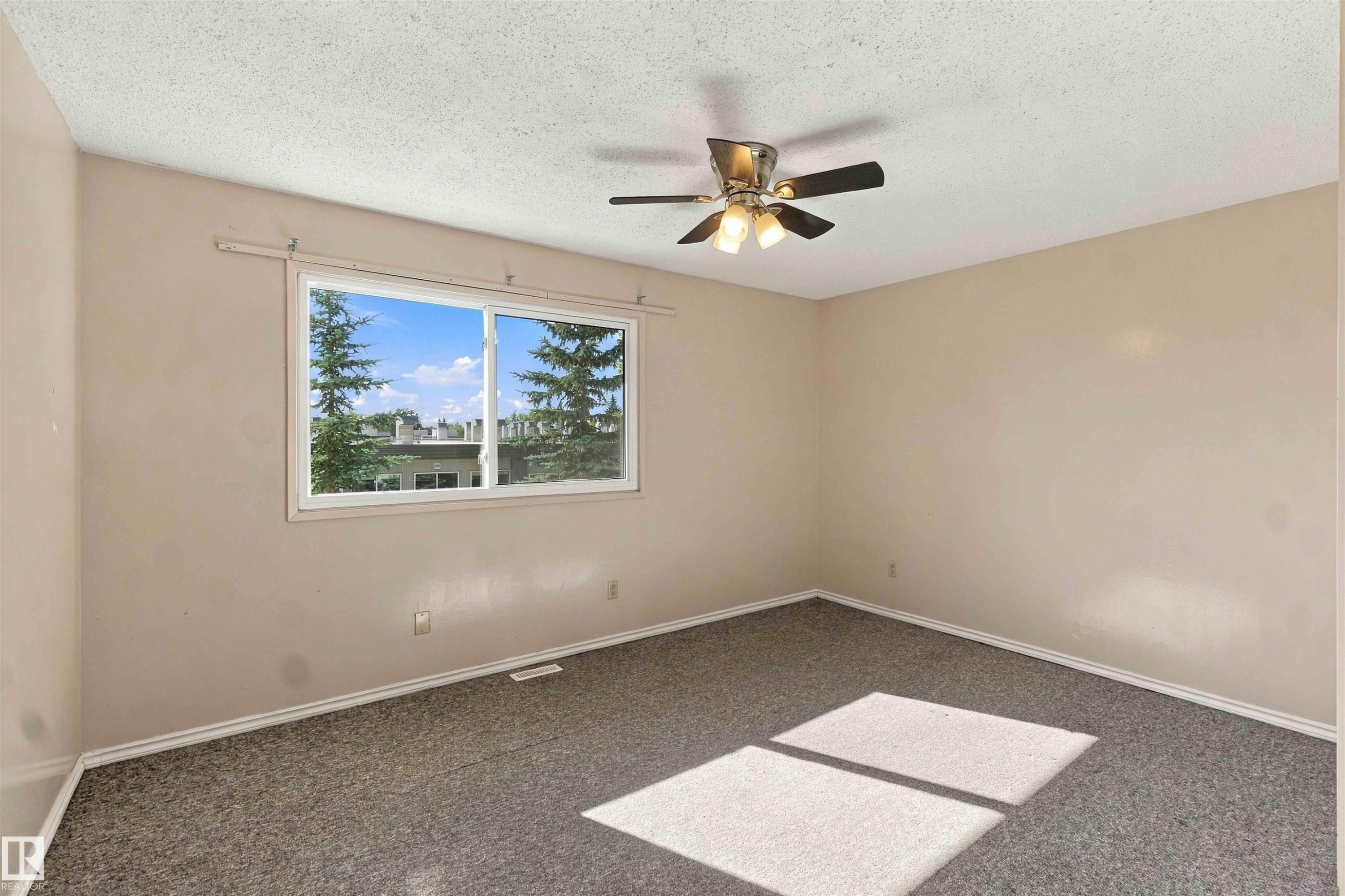 Wall-to-wall carpeting, ceiling fan with light fixture, and a large window - 17351 85 Avenue Nw, Edmonton, AB