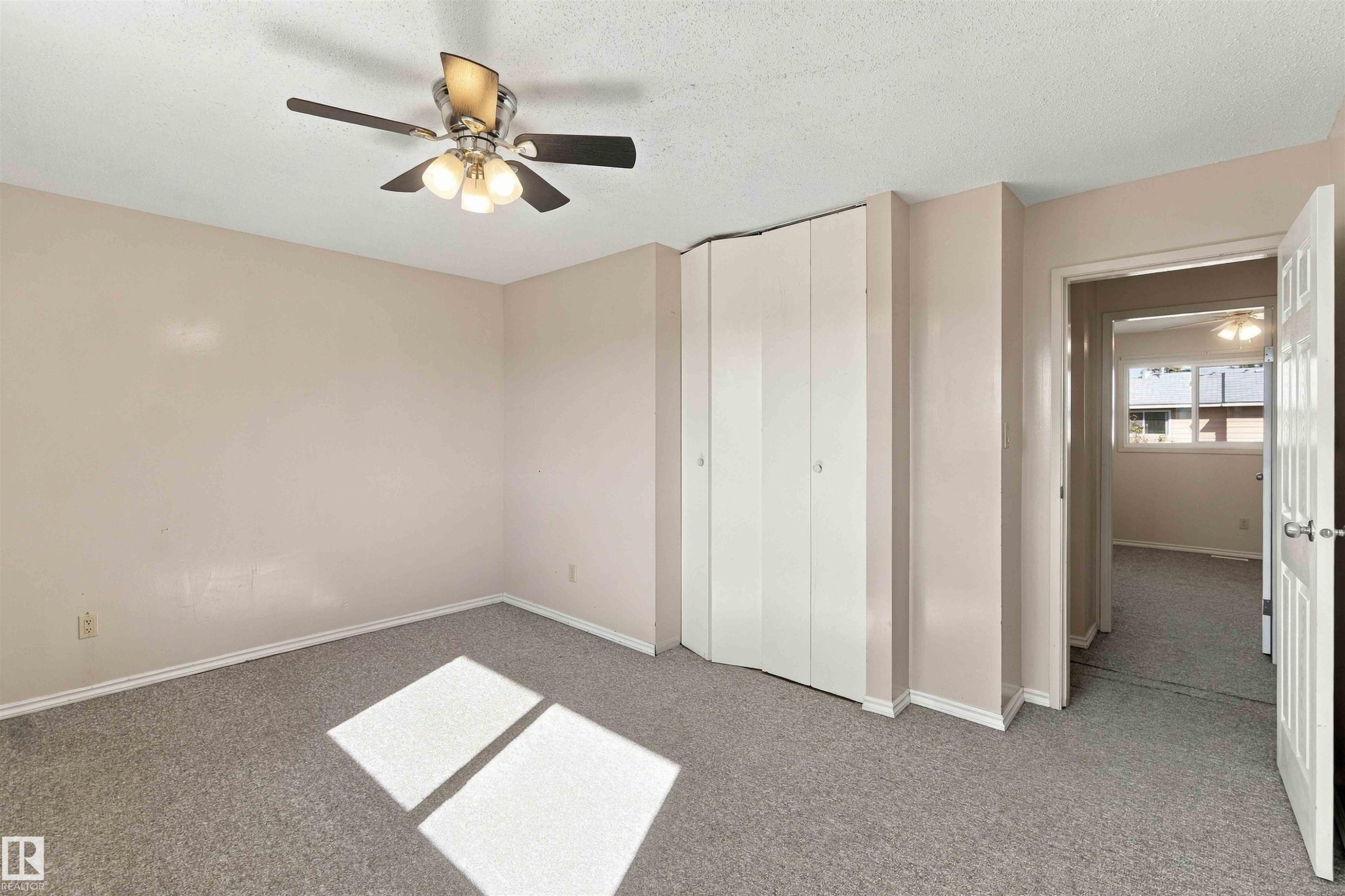 Textured ceiling, ceiling fan with integrated lighting, neutral wall paint, gray carpeting, and bi-fold closet doors - 17351 85 Avenue Nw, Edmonton, AB