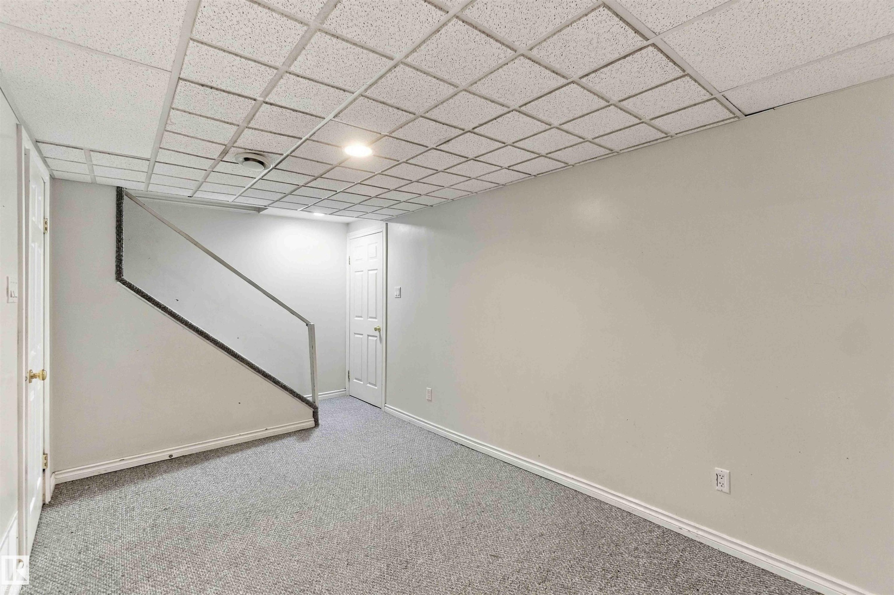Finished lower level with carpet flooring, white walls, and a suspended grid ceiling - 17351 85 Avenue Nw, Edmonton, AB