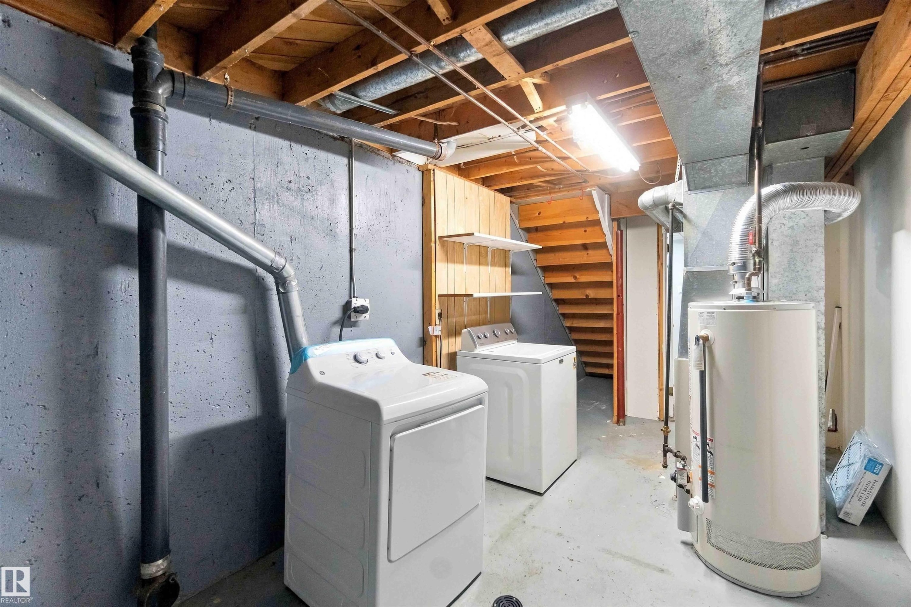 Utility room featuring a water heater, exposed wood joists, concrete flooring, and a stairway with wood treads - 17351 85 Avenue Nw, Edmonton, AB