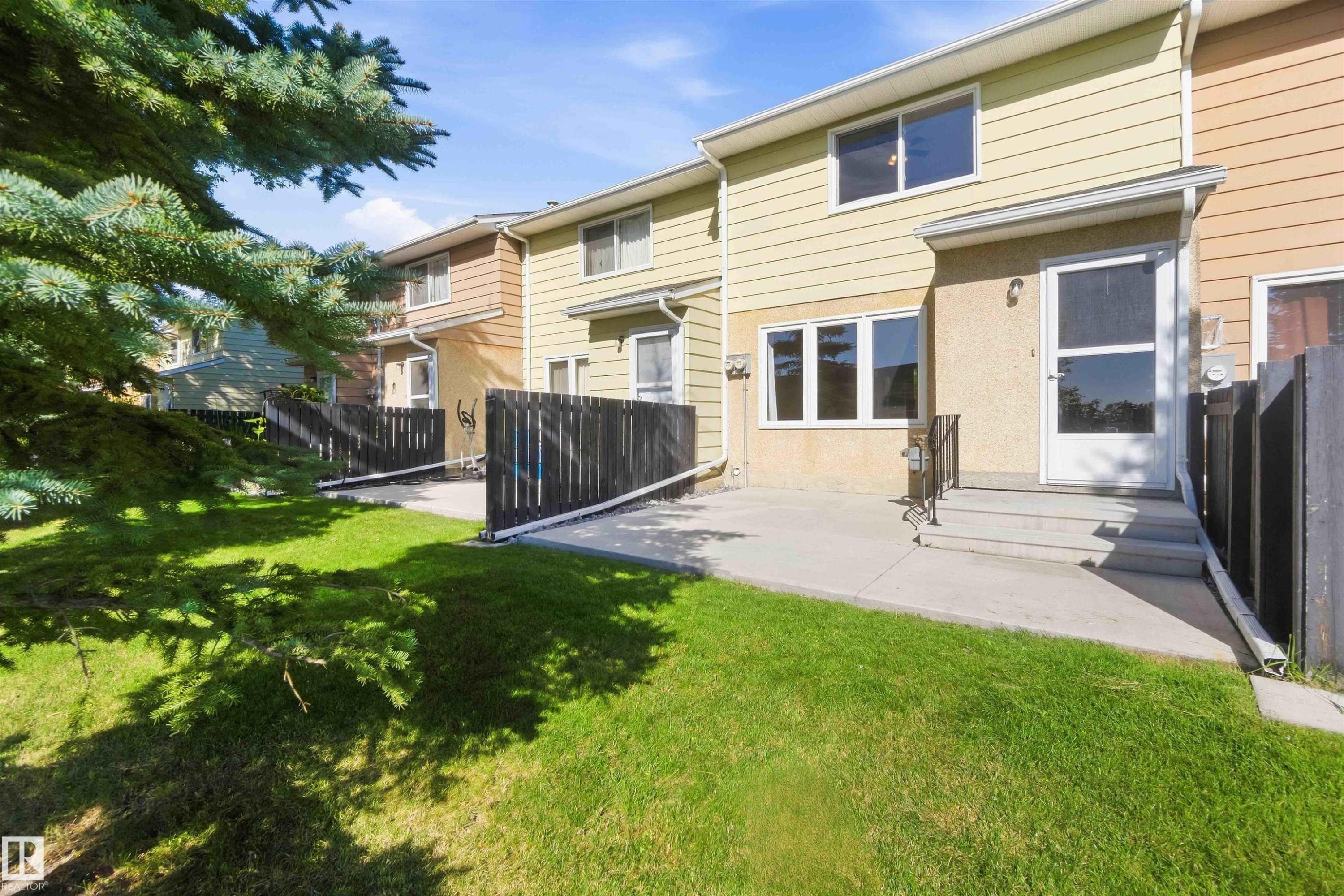 Expansive green lawn, concrete patio, concrete steps with metal railing, and wood siding exterior - 17351 85 Avenue Nw, Edmonton, AB