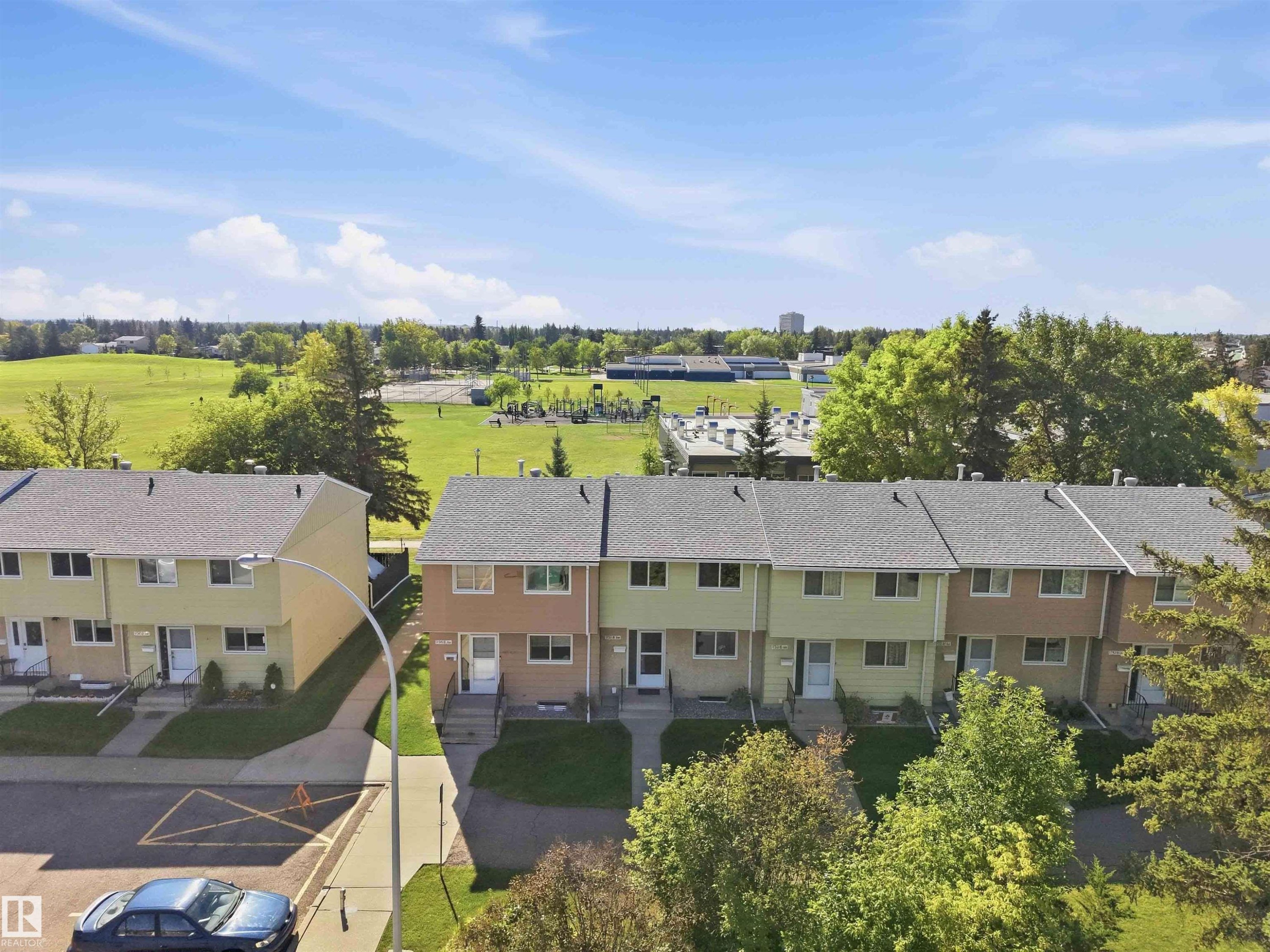 Townhome row with individual entryways, pitched roofs, and mature landscaping - 17351 85 Avenue Nw, Edmonton, AB