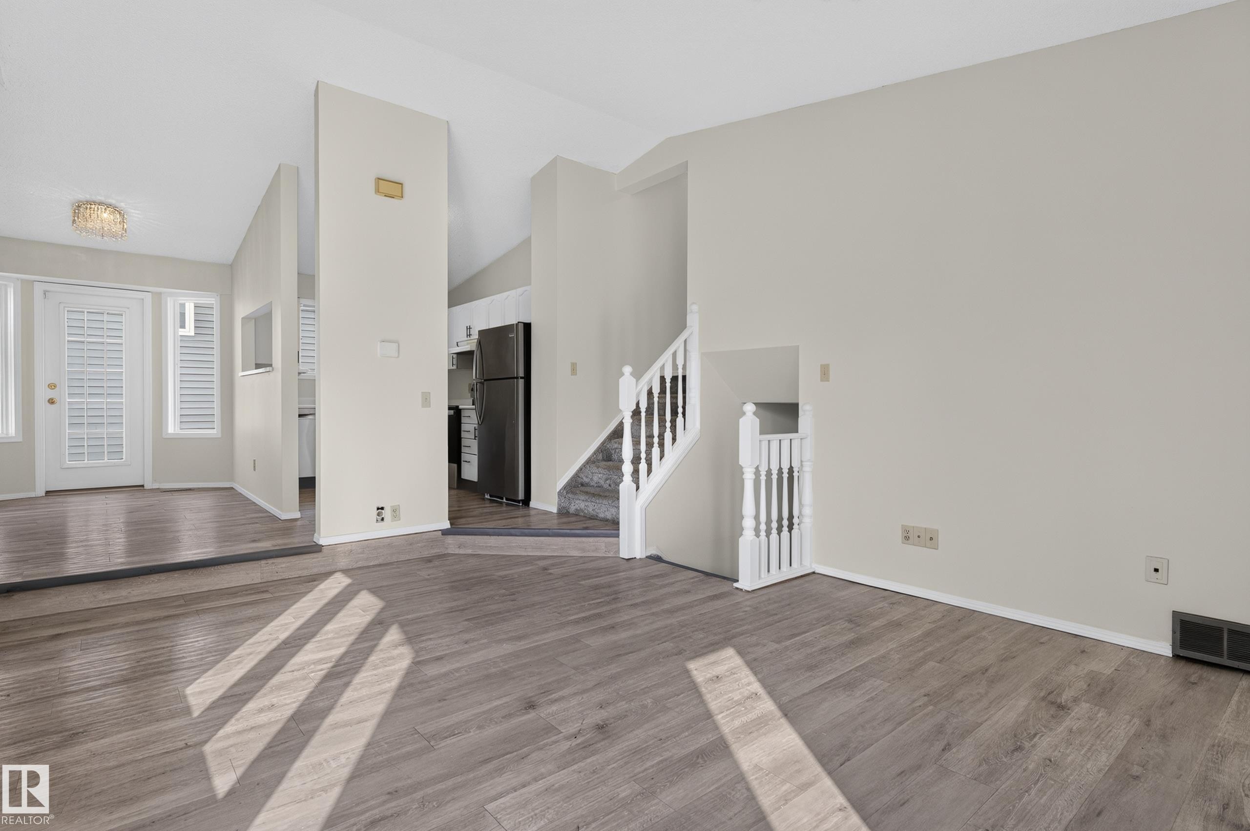 Wood-finish flooring, white walls, white staircase with balusters, and a decorative ceiling light fixture - 3722 34A Avenue Nw, Edmonton, AB