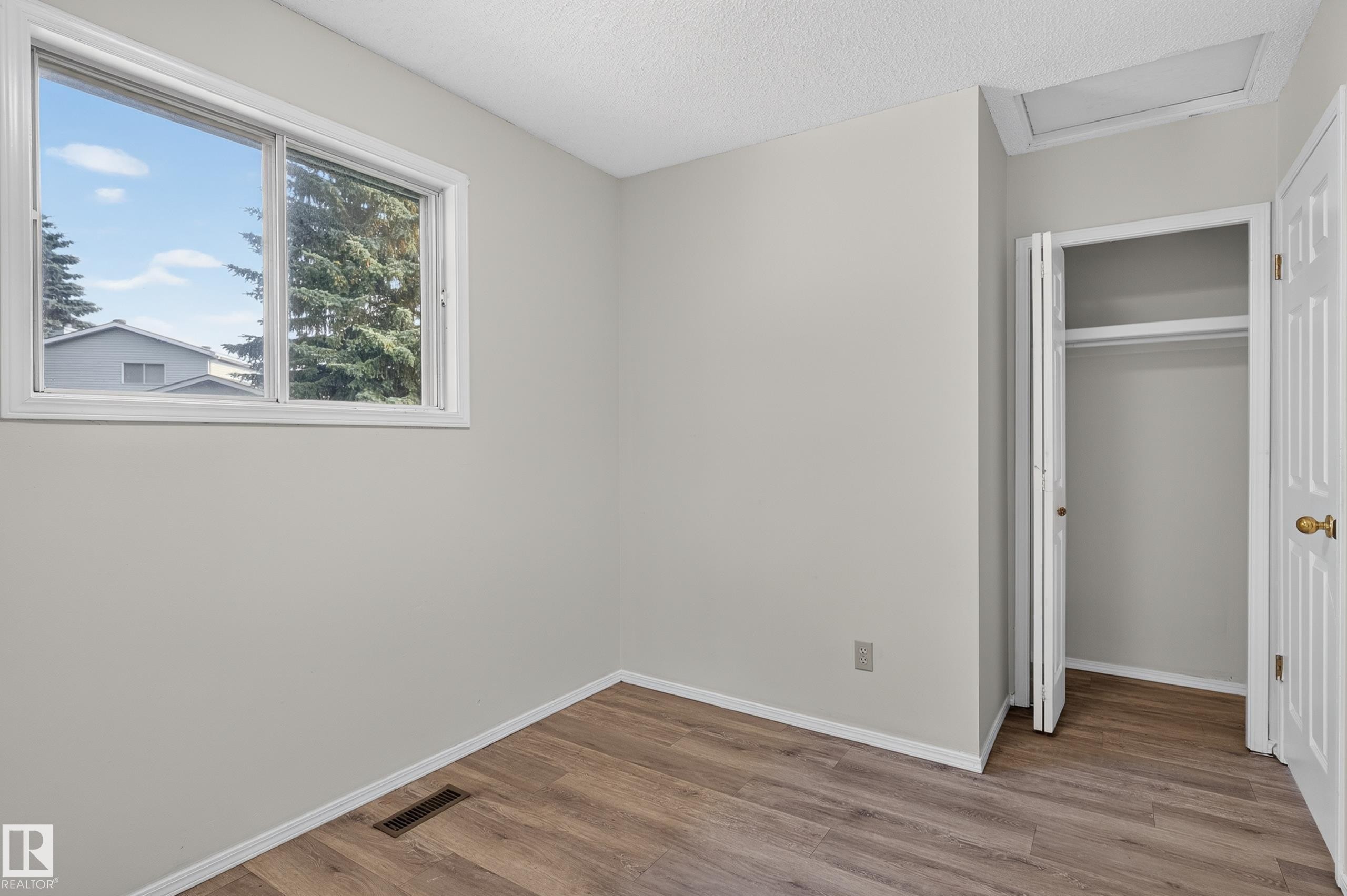Wood-finish flooring, white trim, sliding window, and a bifold door closet with shelving - 3722 34A Avenue Nw, Edmonton, AB