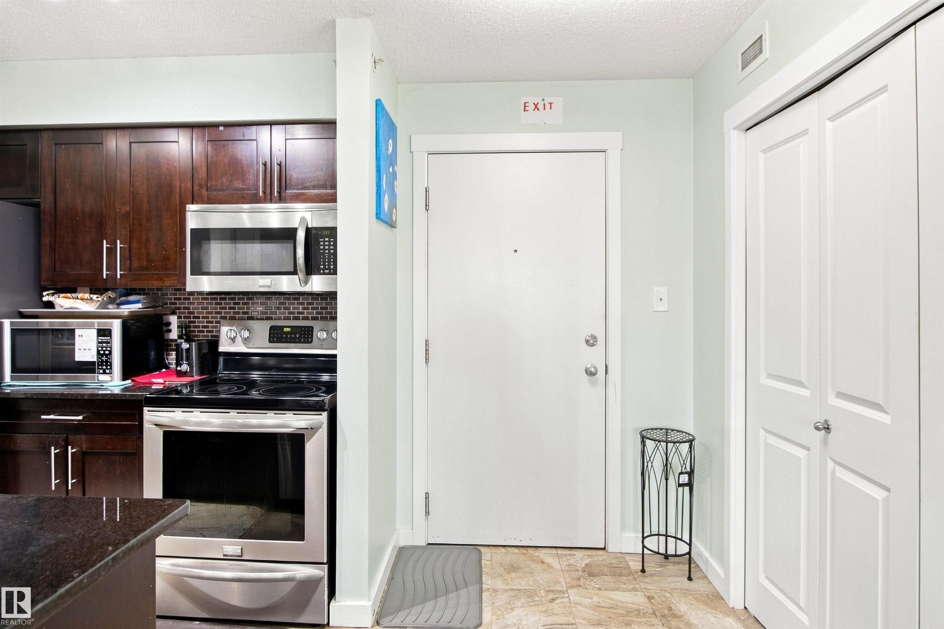 Kitchen featuring wood-finish cabinetry, stainless steel appliances, and a tiled backsplash - #413 18126 77 St Nw, Edmonton, AB