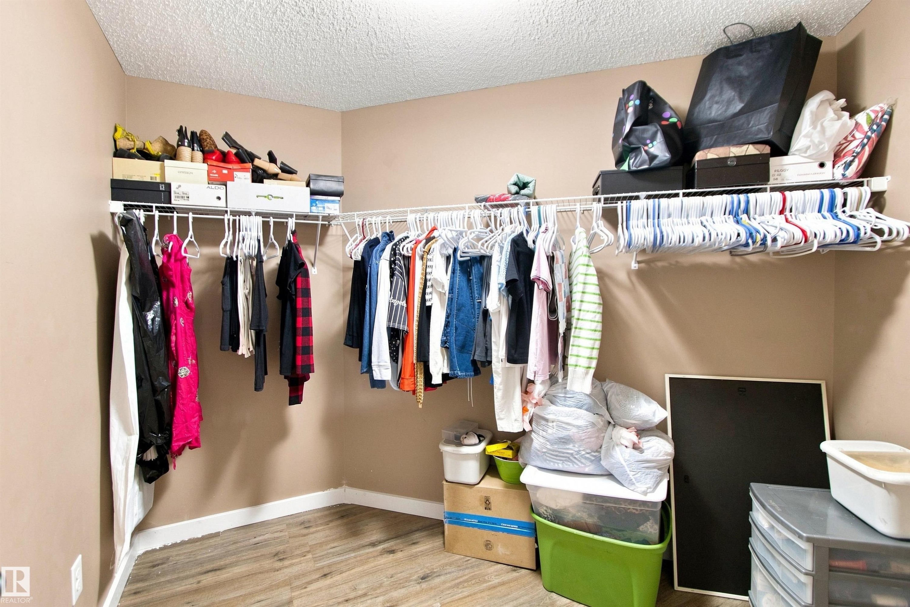 Wood-finish flooring with a neutral wall color, corner shelving, and built-in closet organization - #413 18126 77 St Nw, Edmonton, AB